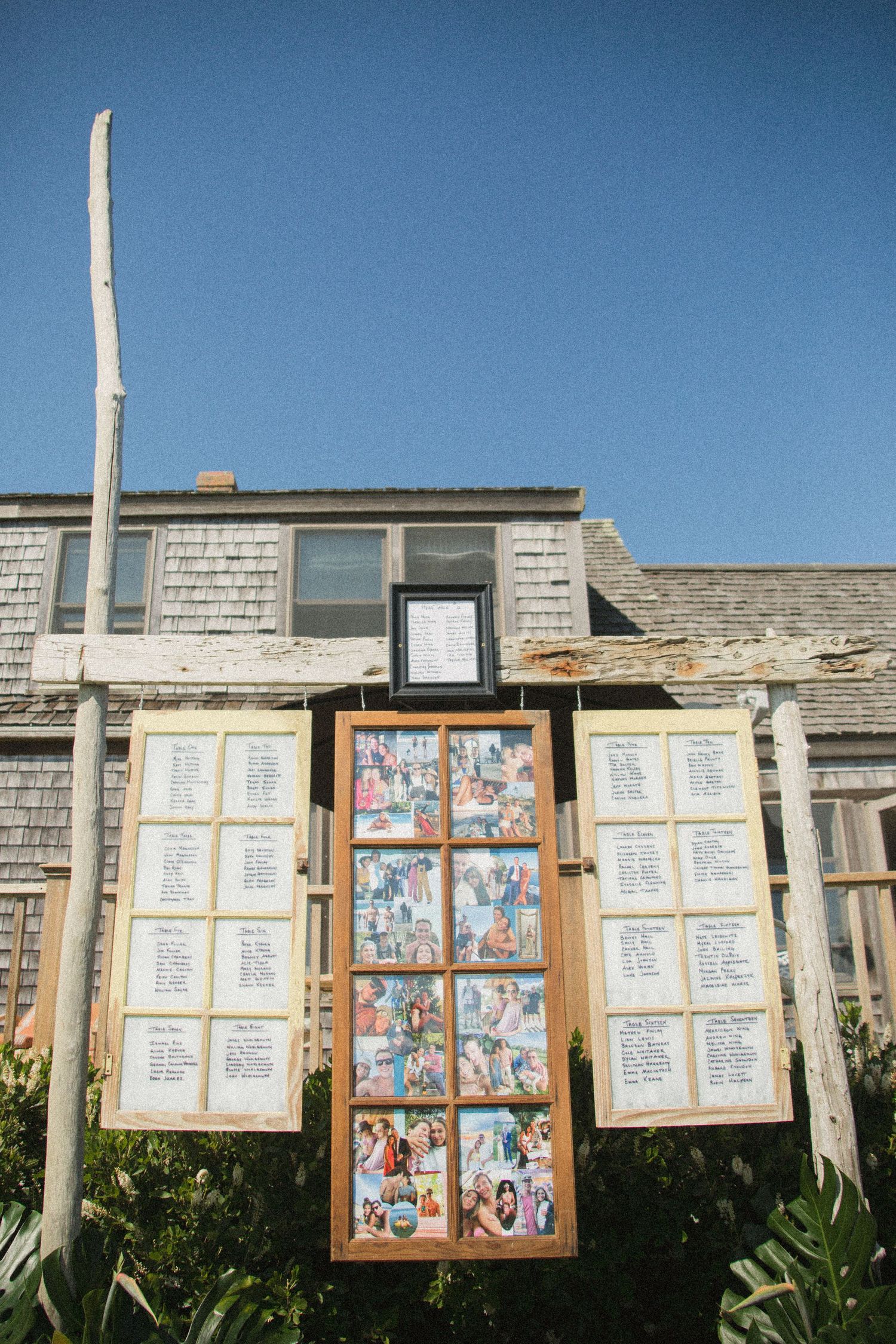 Wooden framed seating charts and photo displays mounted on stone wall under blue sky.