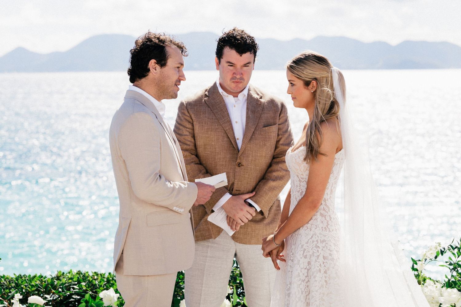 Wedding party members sharing a moment together on a scenic tropical beach overlook.