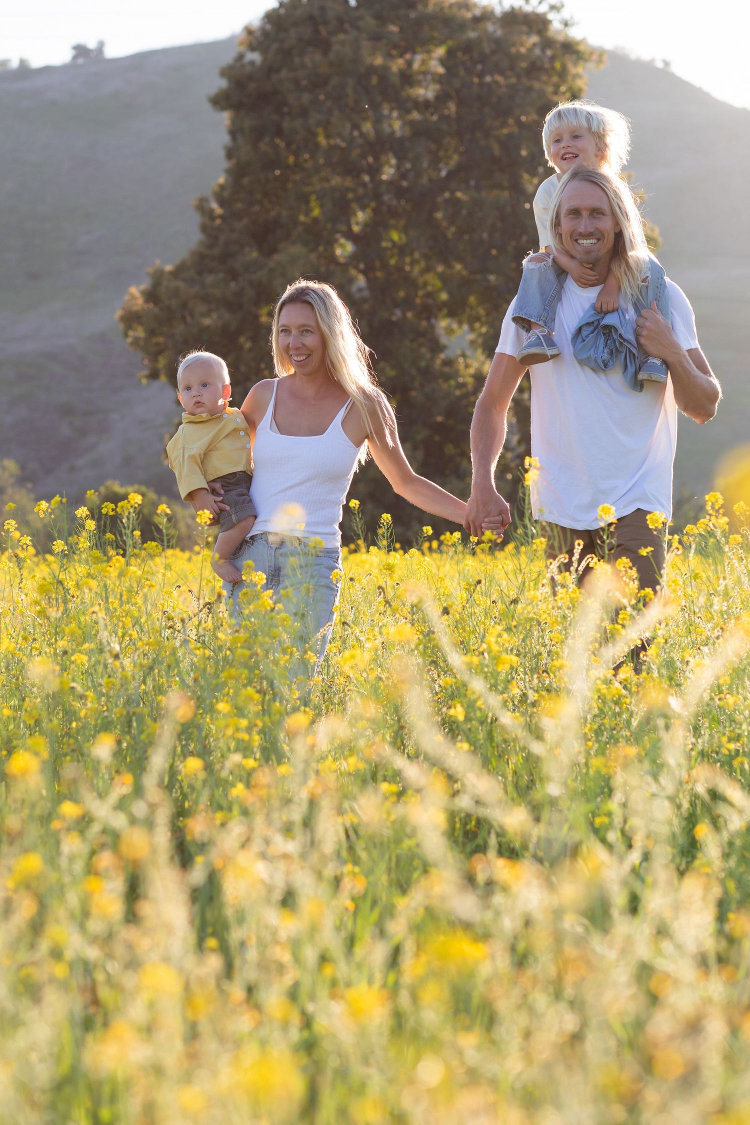 People enjoying a casual moment together in a field of yellow wildflowers at sunset.