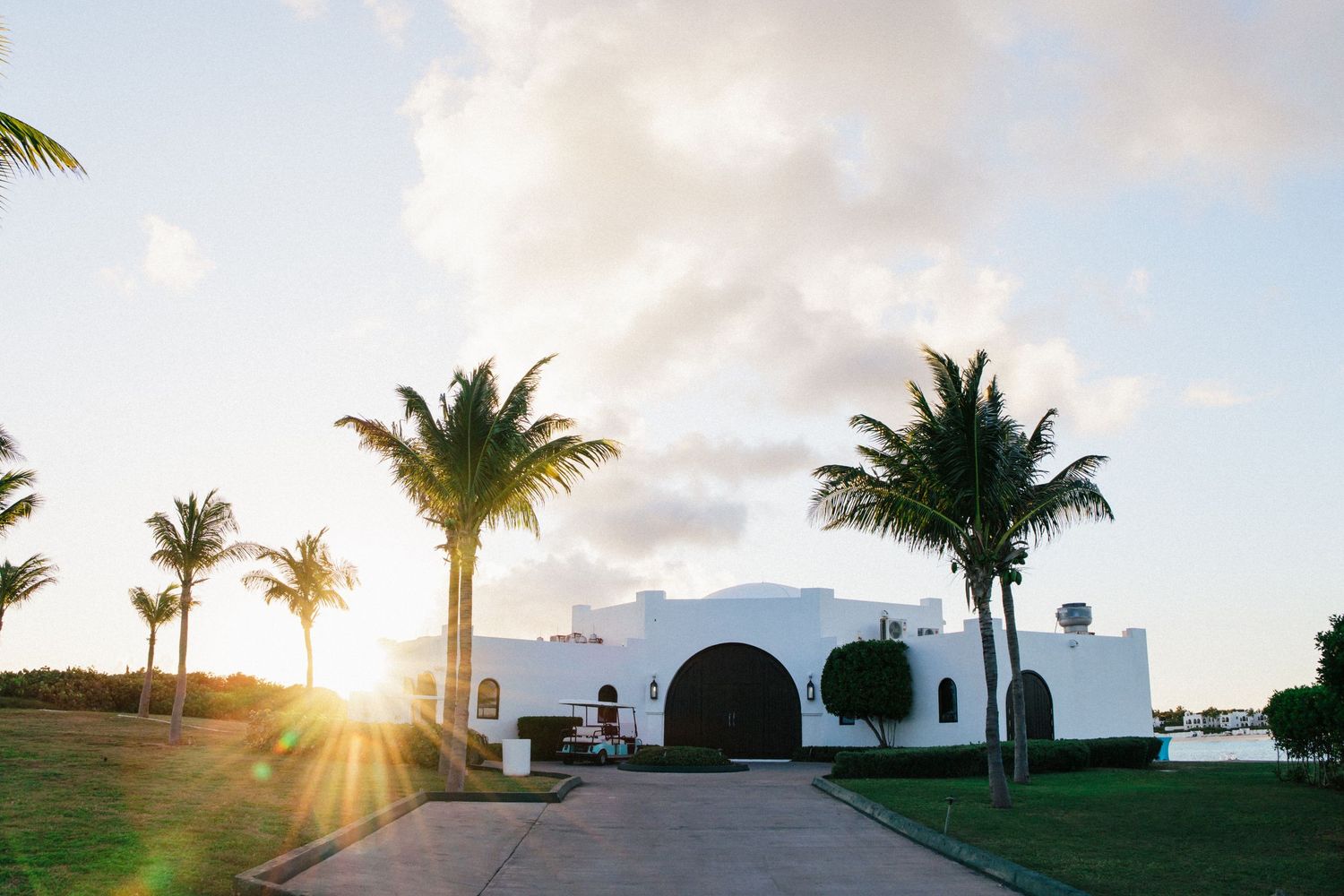White Mediterranean style building with palm trees and sunset at a luxury resort.
