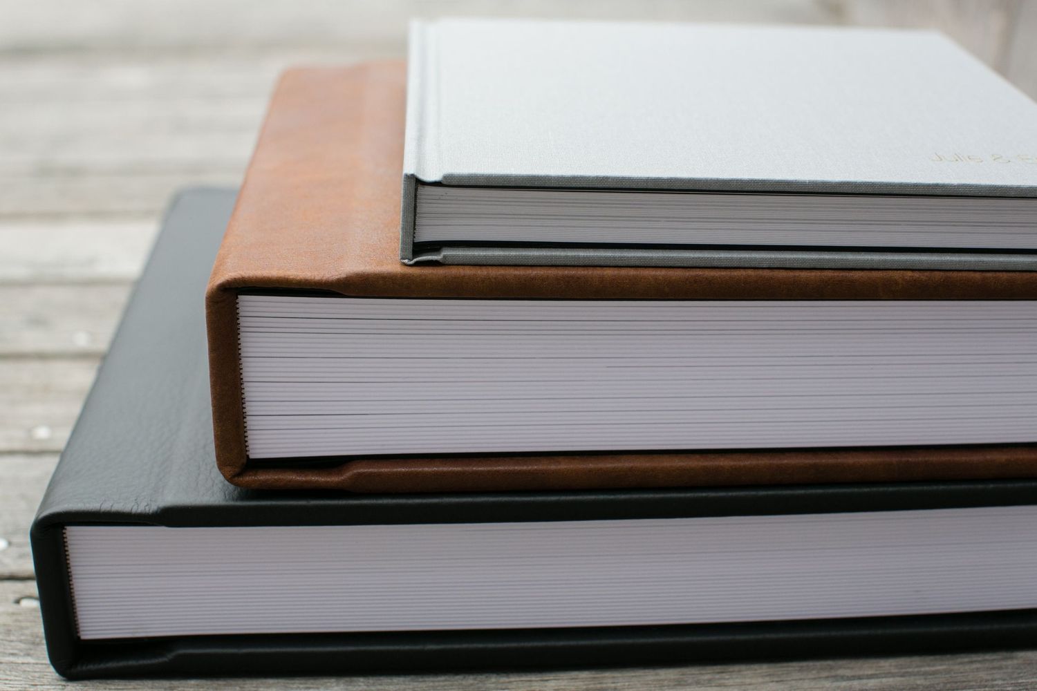 Side view of thick white pages in a professional wedding photo album against wood surface.