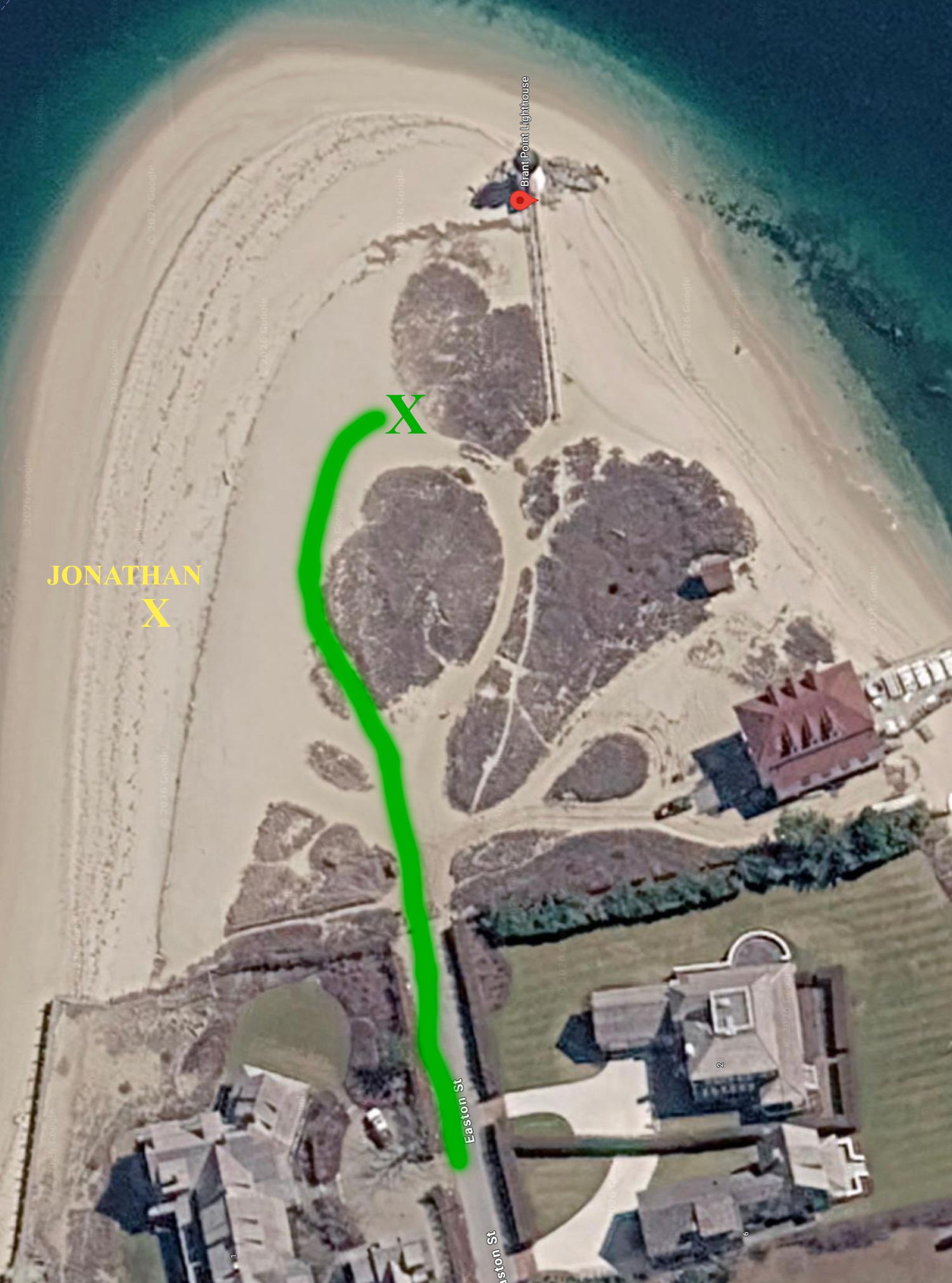 Aerial satellite view of a sandy coastal peninsula with a green path marked leading to a lighthouse, with text annotations.