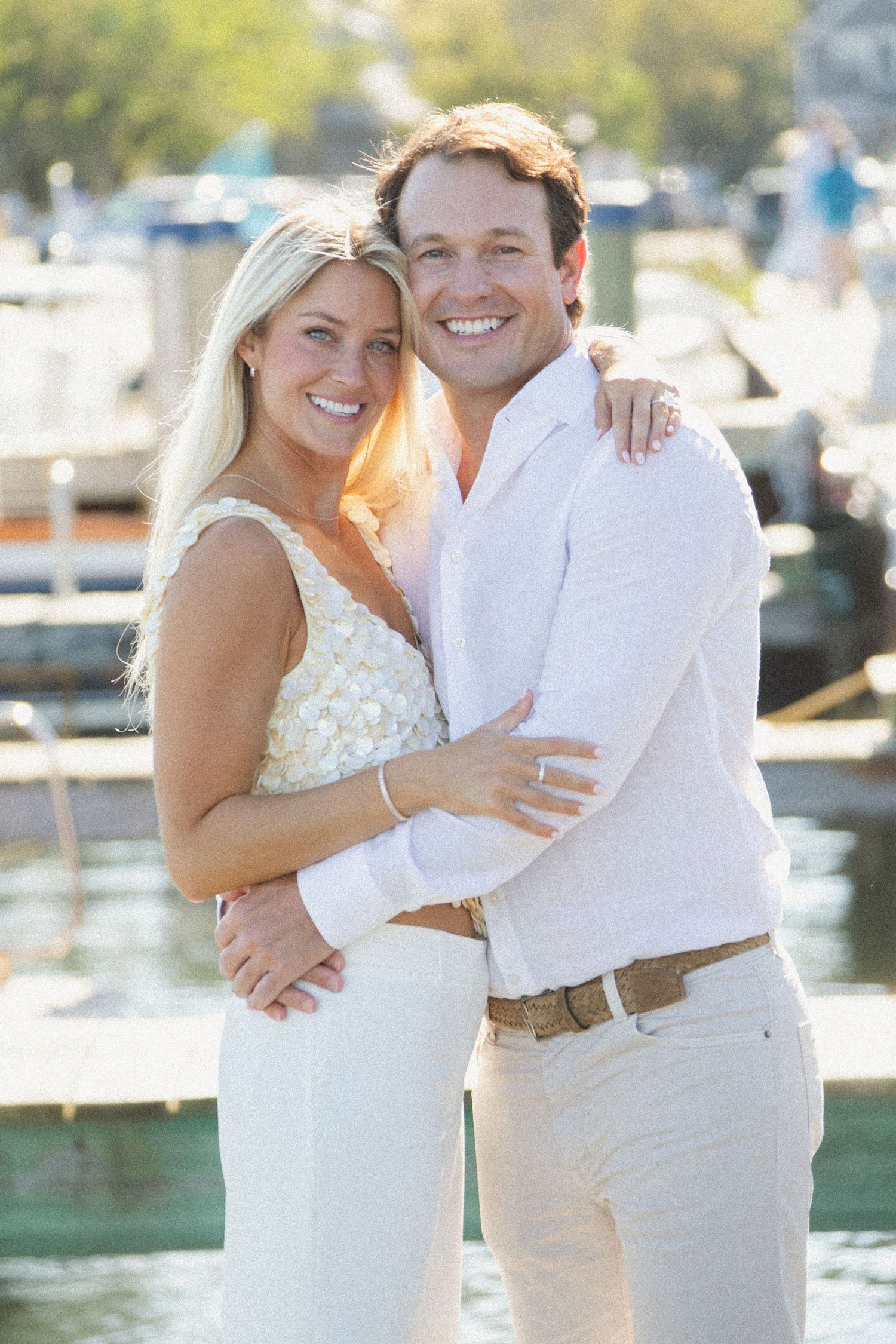 Romantic waterfront photo shoot with couple in white outfits by marina dock.
