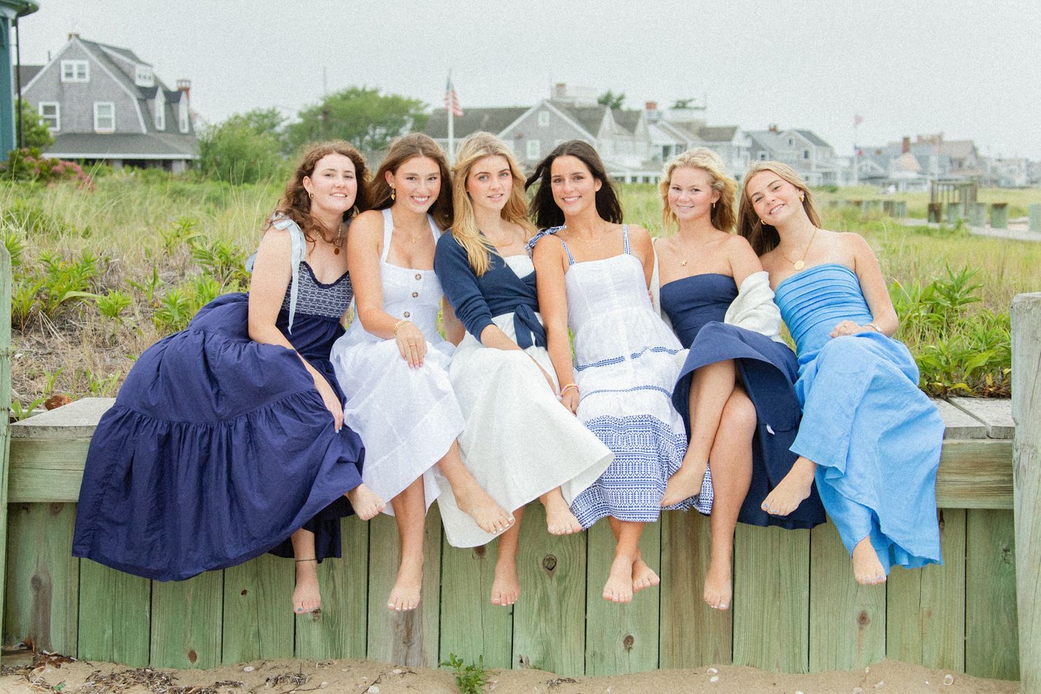 Row of bare feet dangling over a wooden fence during a summer photo shoot.