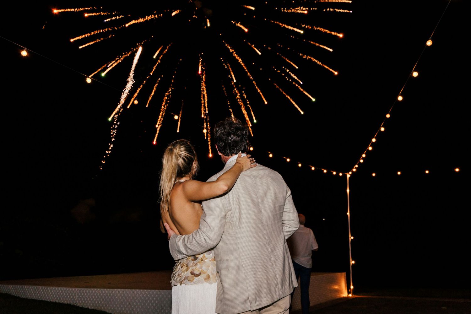 Glowing fireworks create a spectacular display in the night sky above celebrating guests.