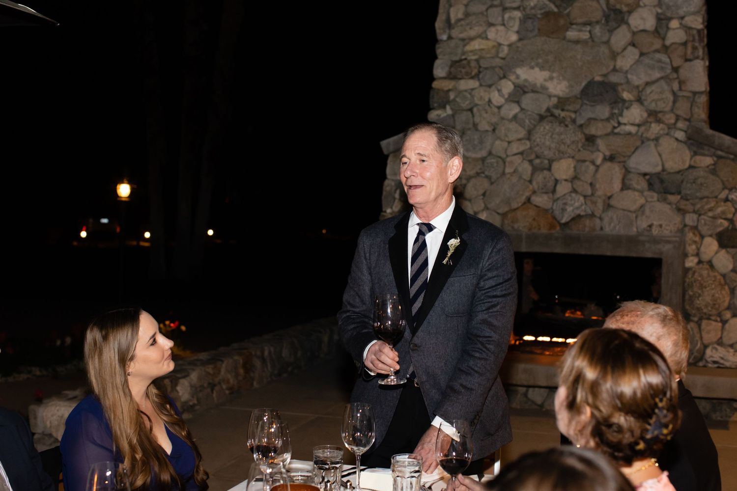 Wedding reception dinner in a rustic stone-walled venue with guests seated at long tables.