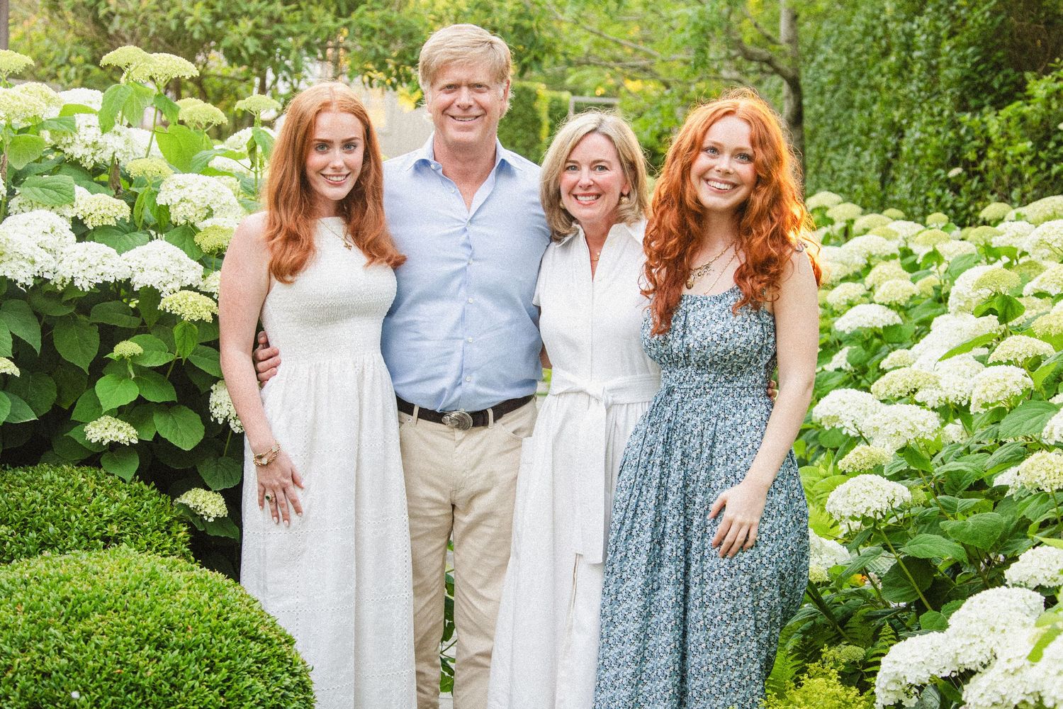 Garden portrait session with white hydrangea bushes in full bloom.