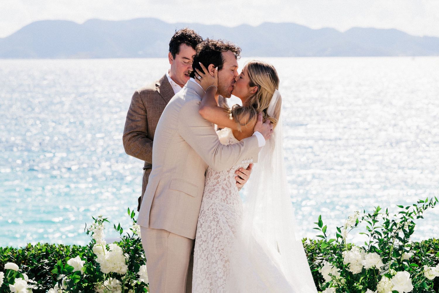 Seaside wedding ceremony featuring elegant white floral arrangements and ocean views.