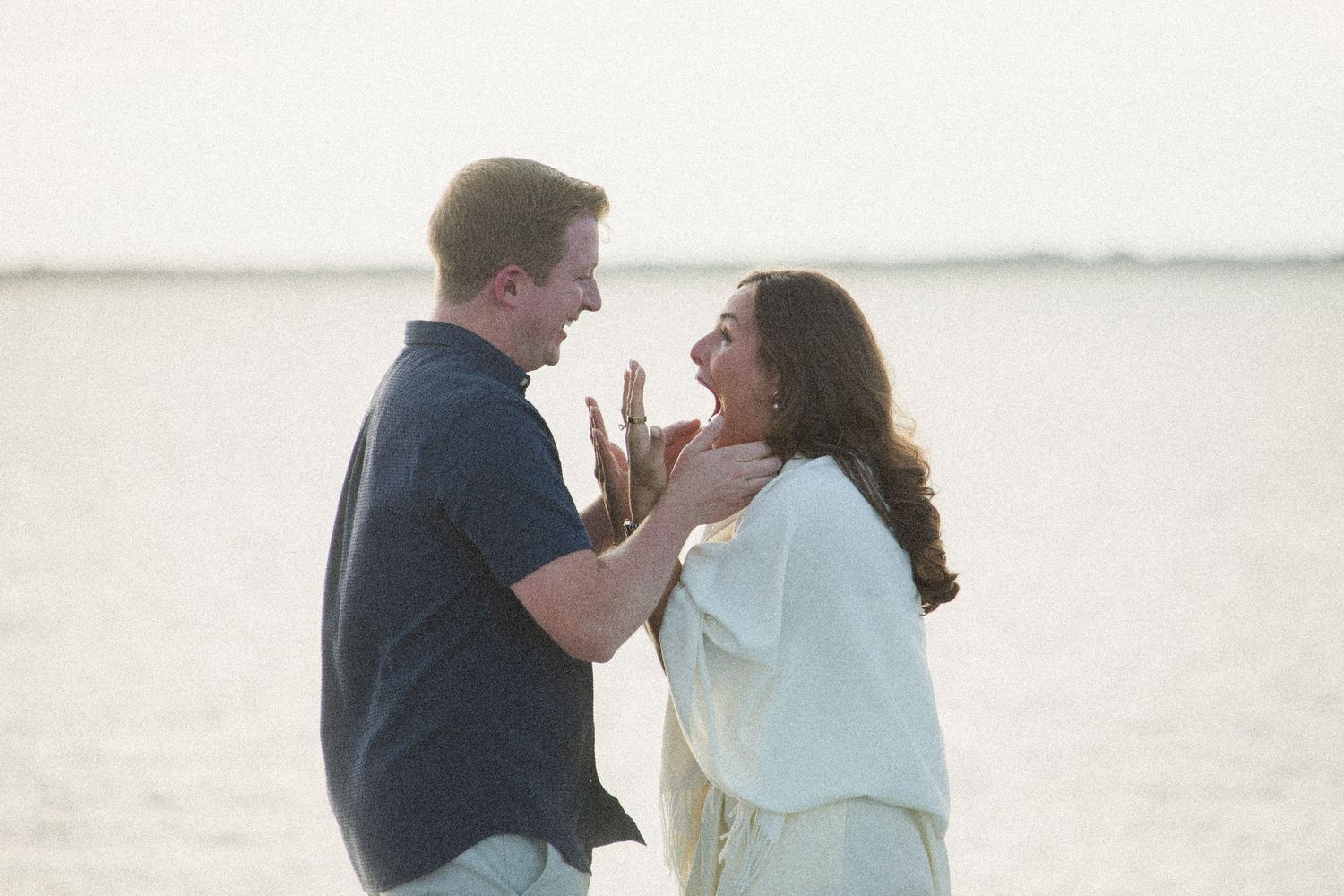 A couple celebrates an emotional moment by the water at sunset.