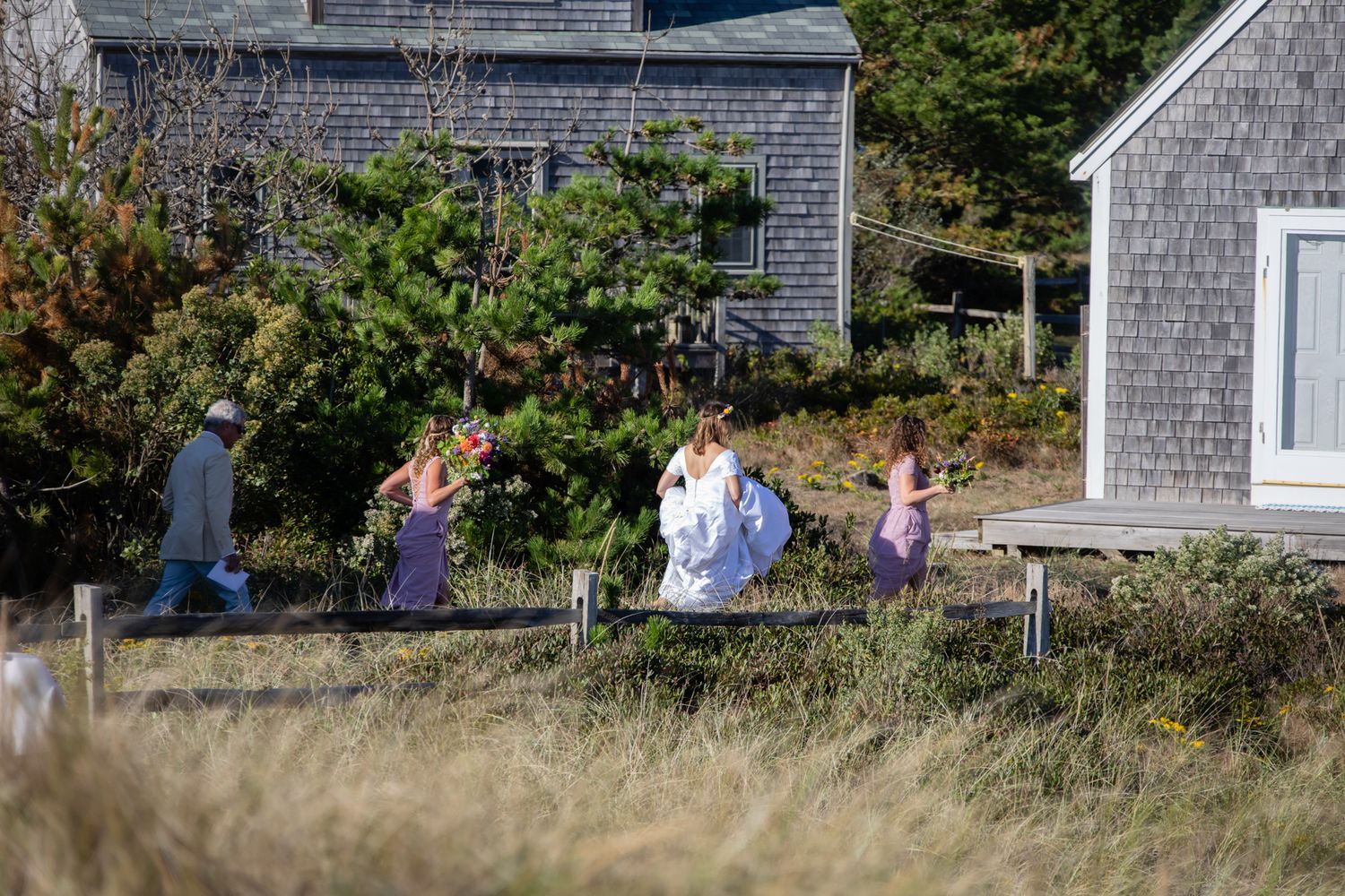 Wedding guests gathered outside a coastal New England style home with grey shingles.