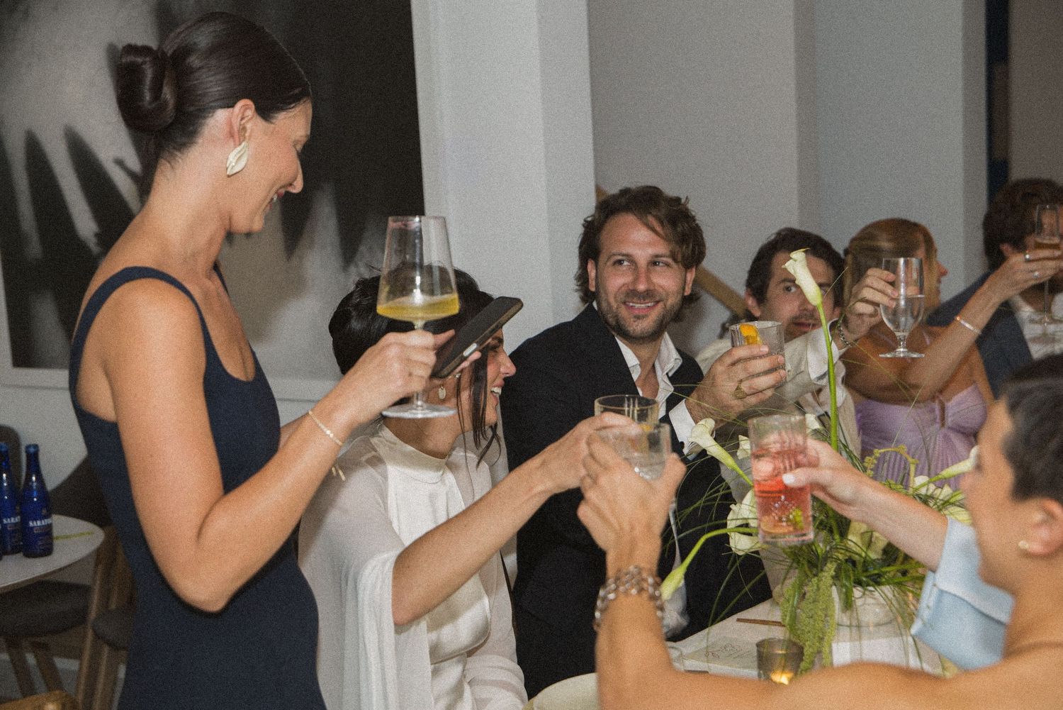 Guests raising glasses in a celebratory toast at an elegant indoor dinner party event.