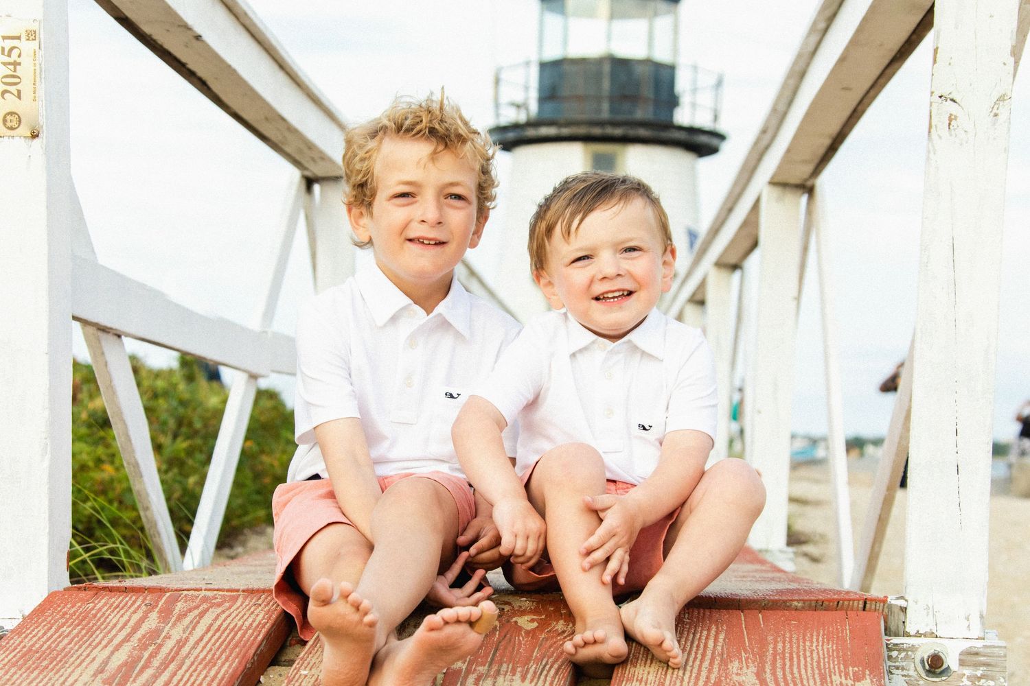 Coastal lighthouse photo session with white wooden railings and natural lighting.