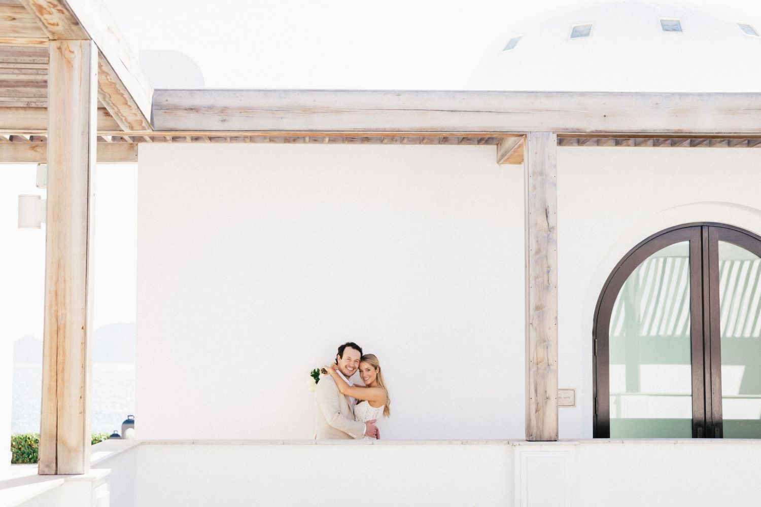 A tender wedding moment photographed against clean white Mediterranean architecture.