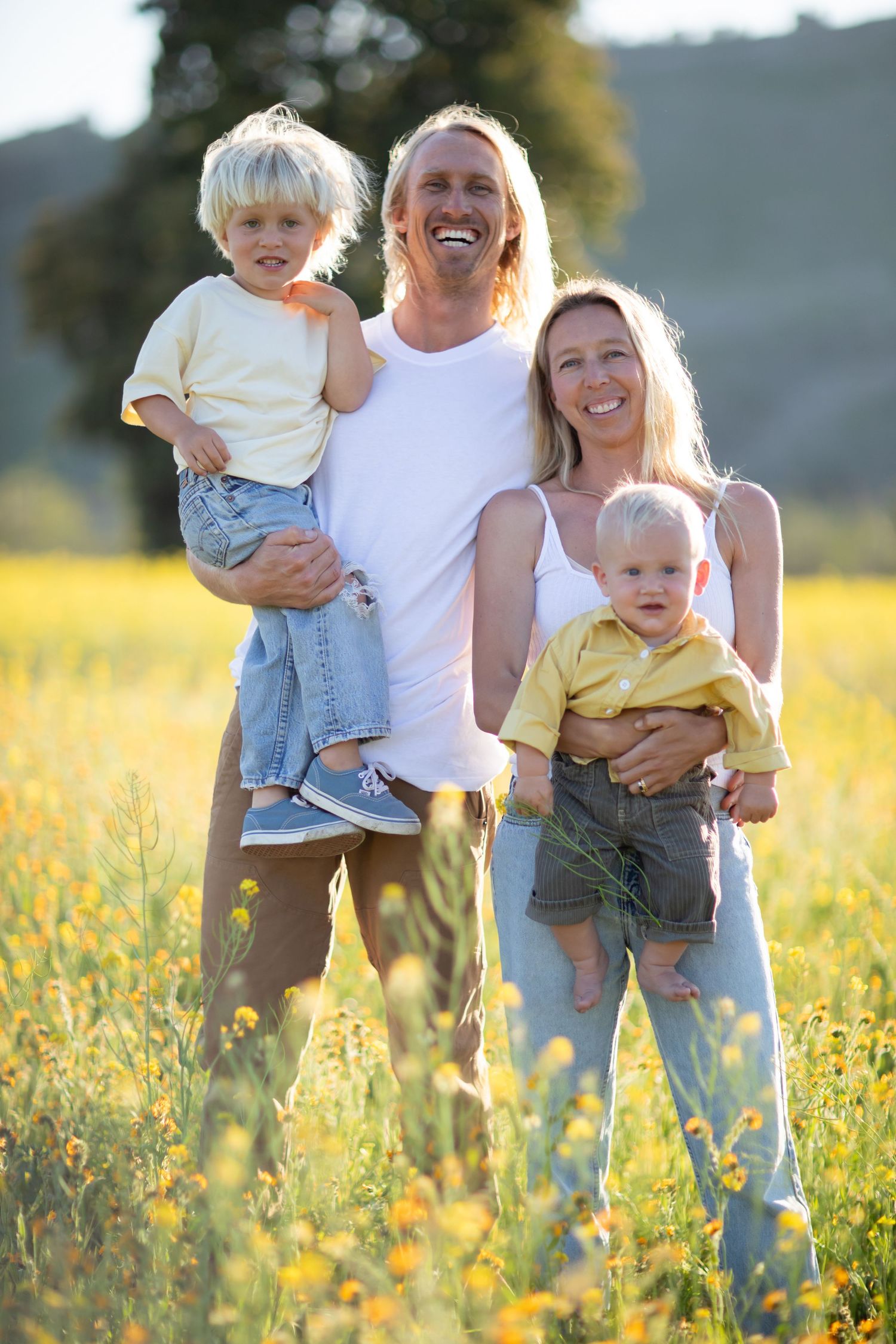 A group poses together in a sunny meadow filled with yellow wildflowers.