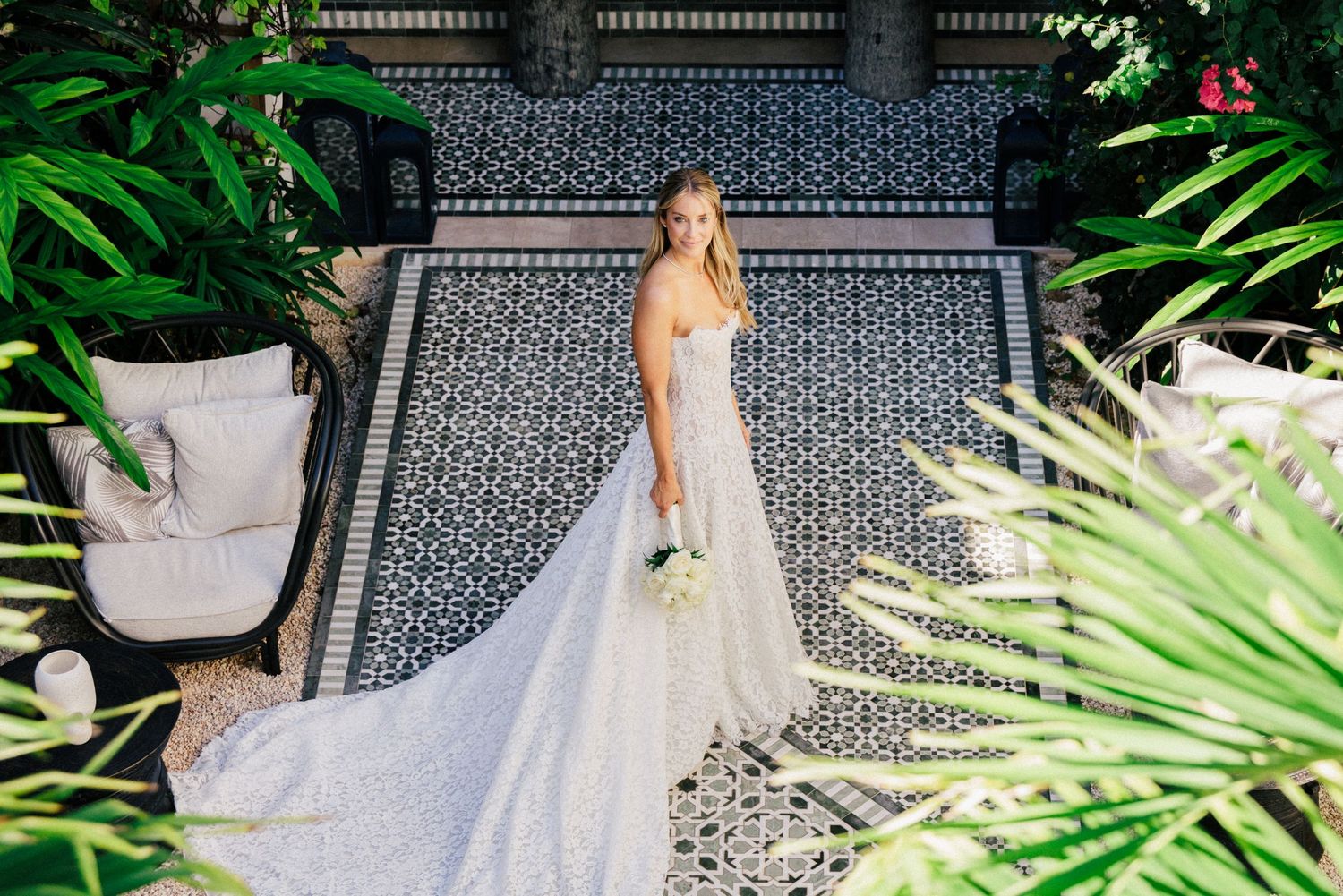 A stunning bridal portrait in a white gown against tropical foliage and patterned tile.