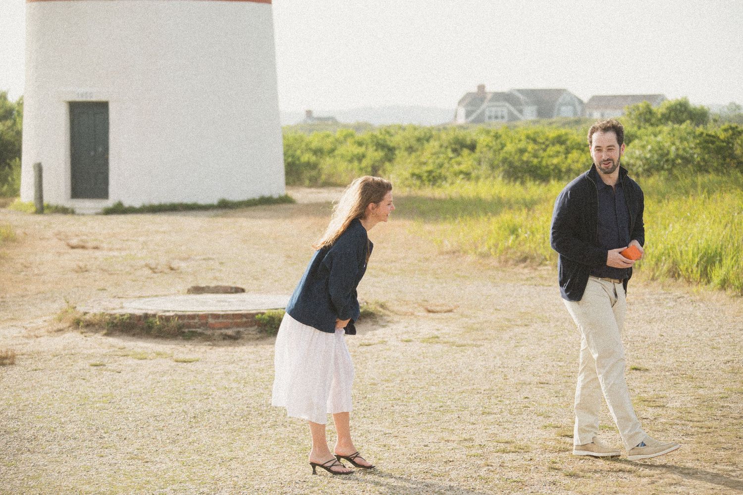 Couple enjoying scenic lighthouse grounds during golden hour.