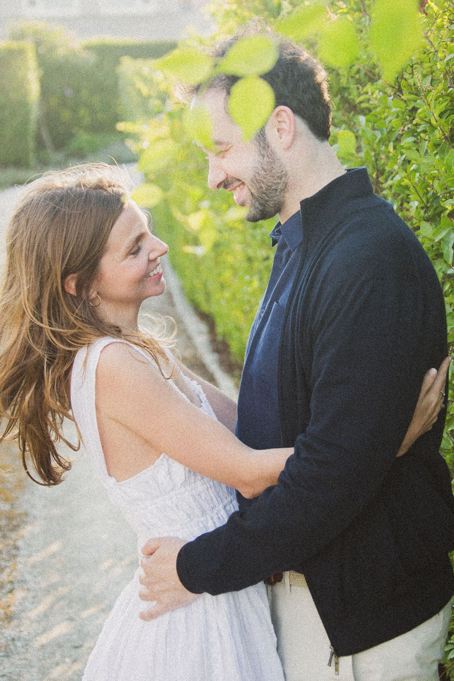 Candid engagement photos capture joyful moments between a couple in a lush outdoor setting.