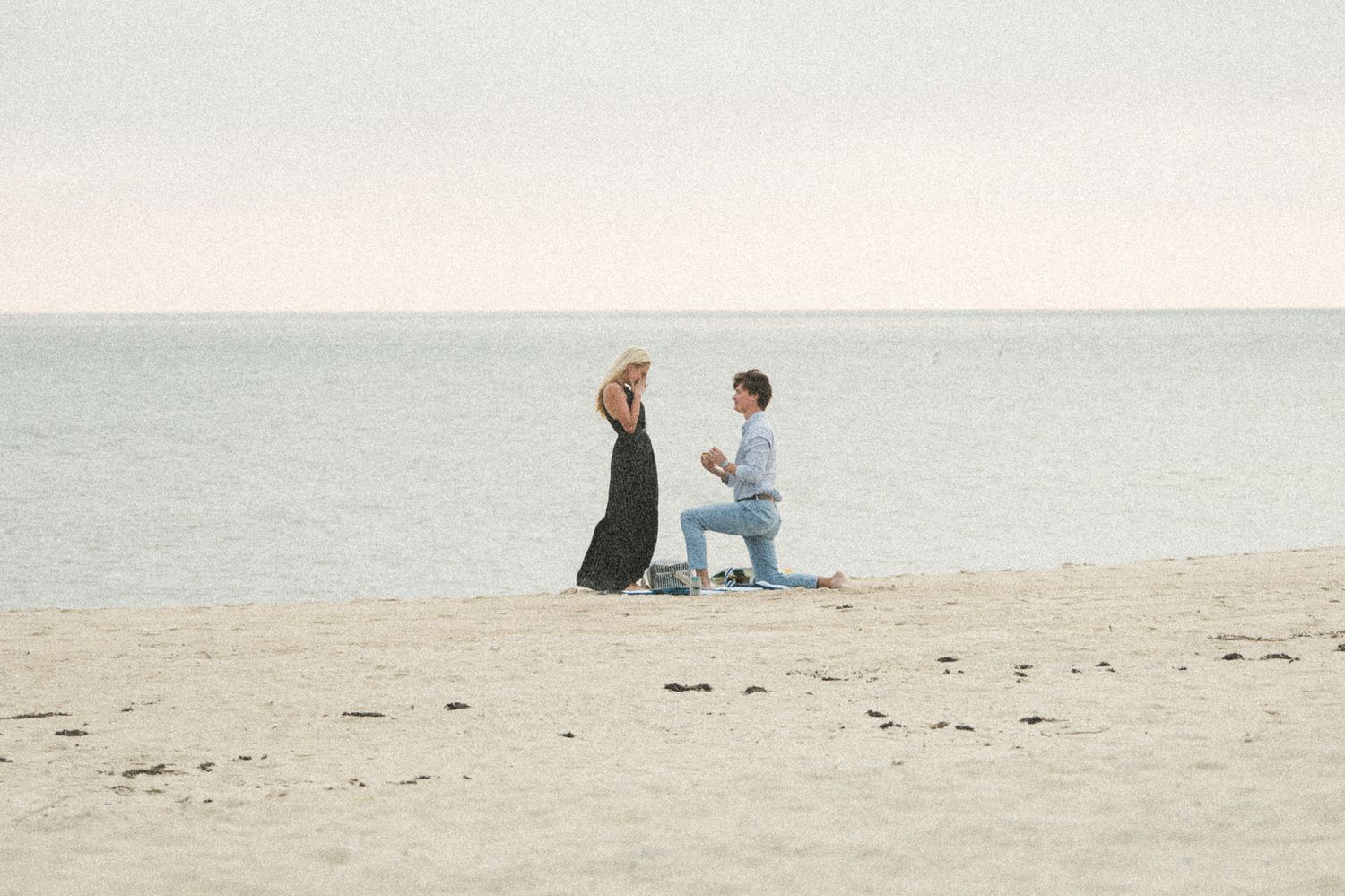 A couple shares a romantic moment on a sandy beach during sunset.