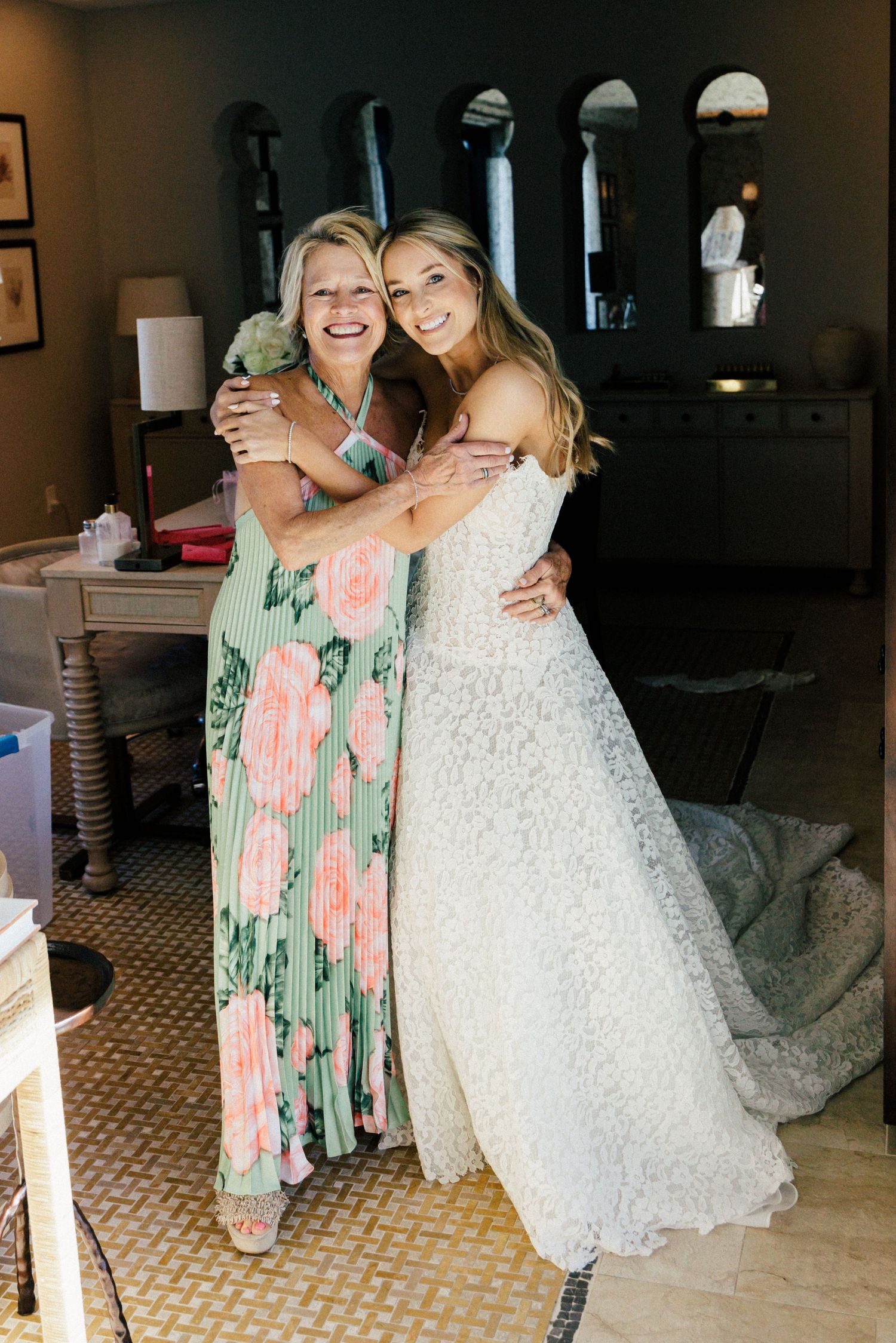 Wedding celebration with bride in white lace gown and guest in floral dress.