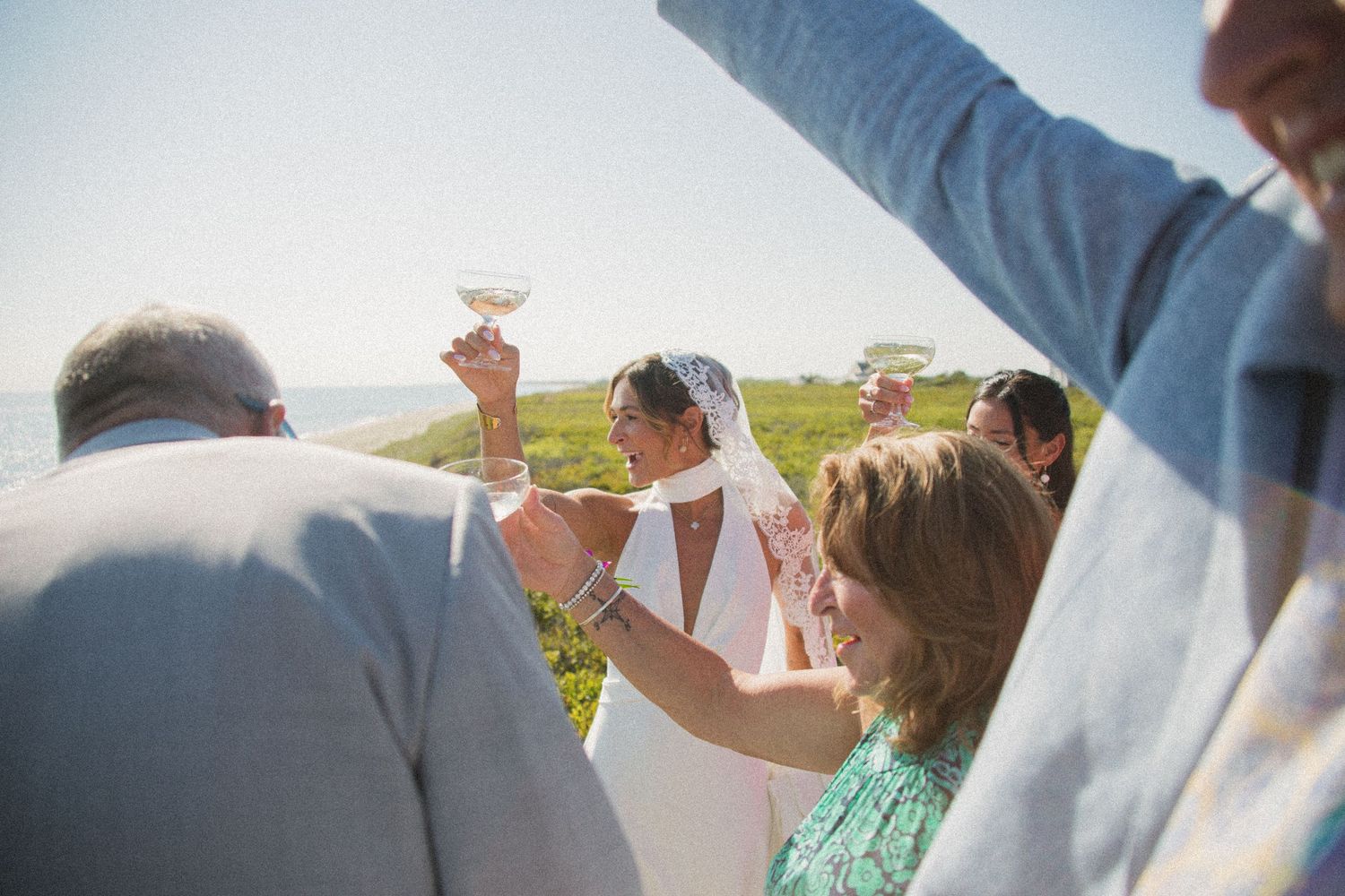 Guests toast with champagne glasses during sunset beach celebration.