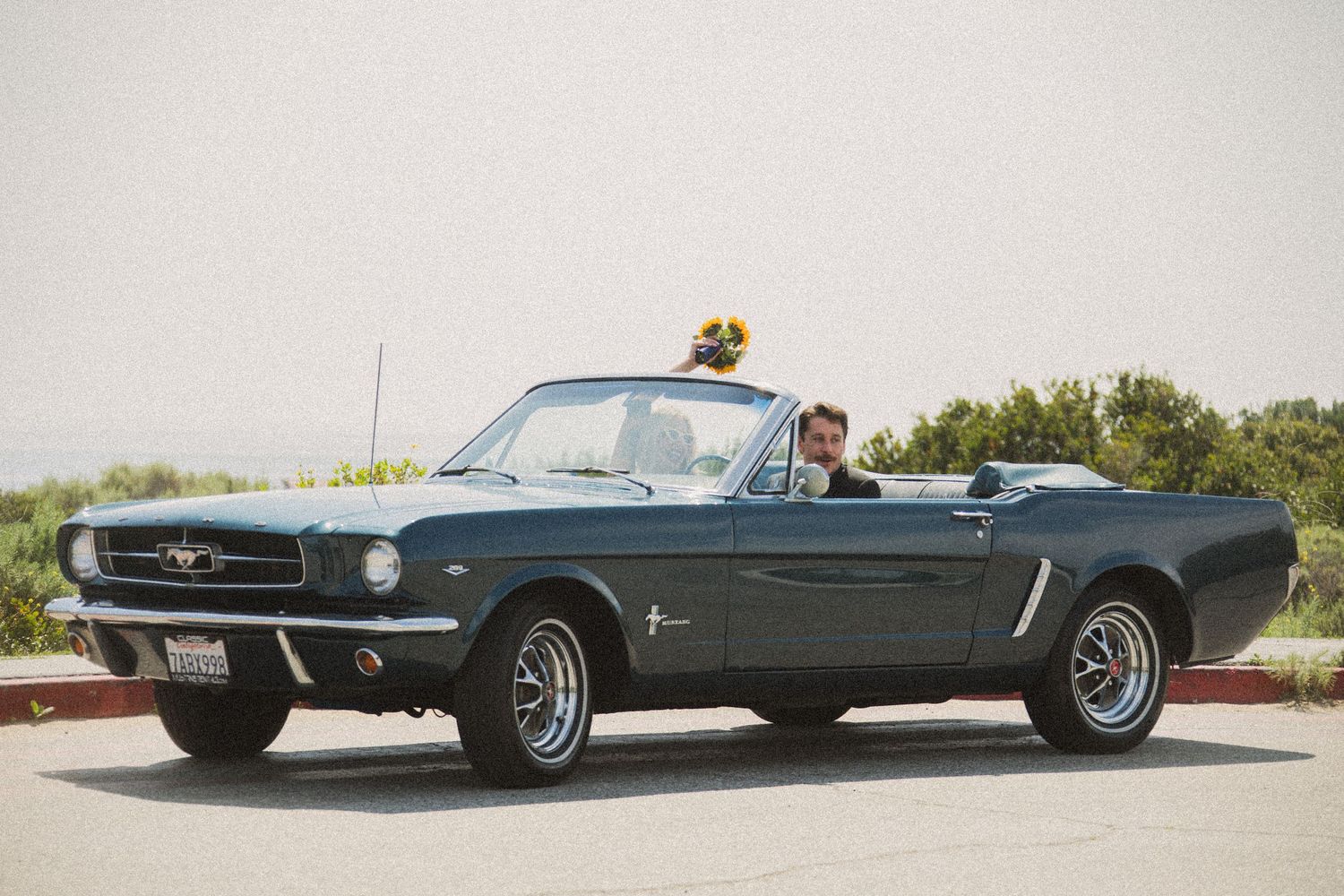 Black vintage Ford Mustang convertible photographed from multiple angles on mountain road.