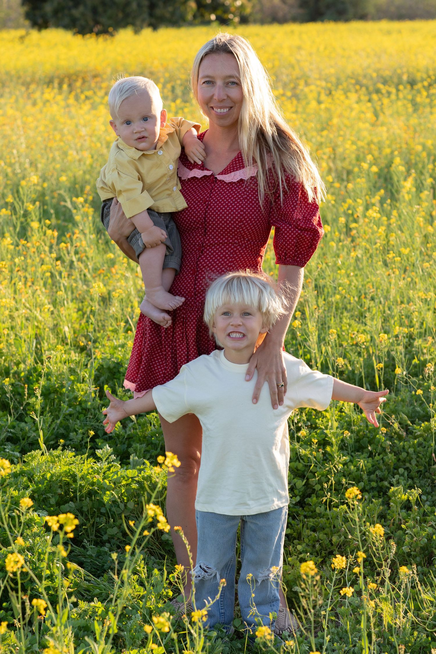 A cheerful family gathering in a field of blooming yellow wildflowers during sunset.