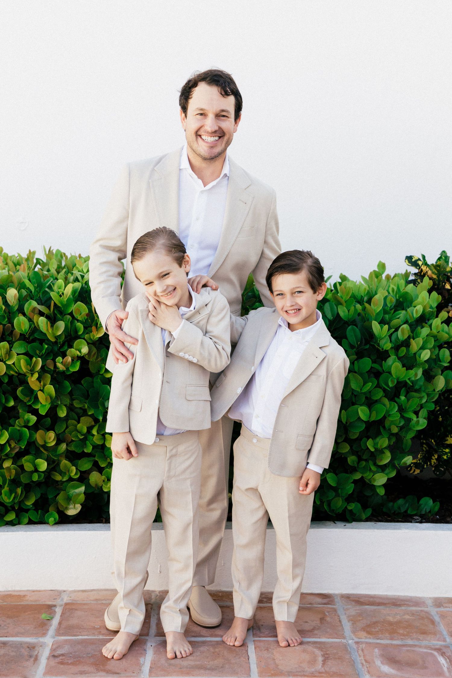 Candid moment of family members in beige suits laughing together outdoors.