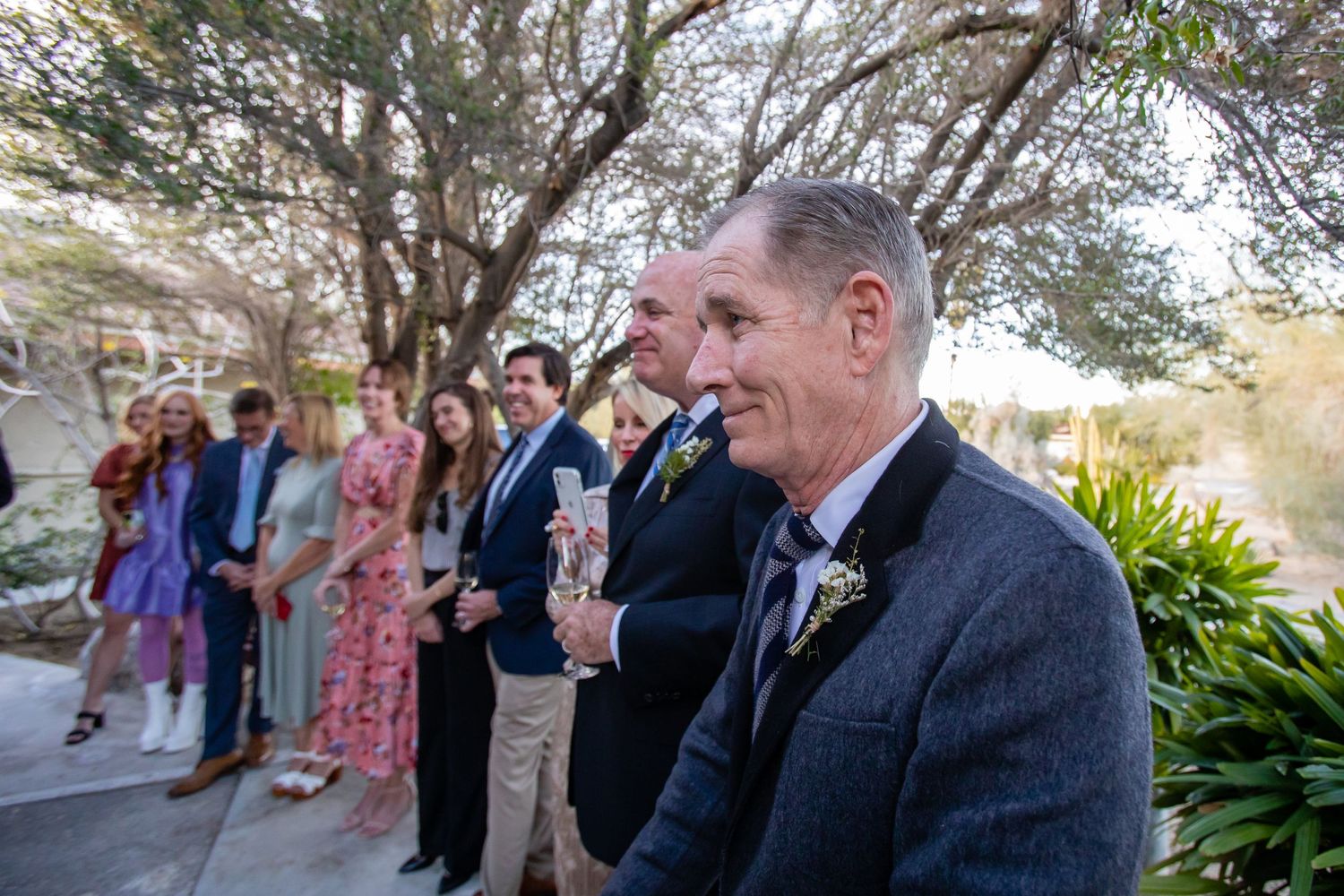 A couple shares a joyful moment during an outdoor ceremony with guests looking on in the background.