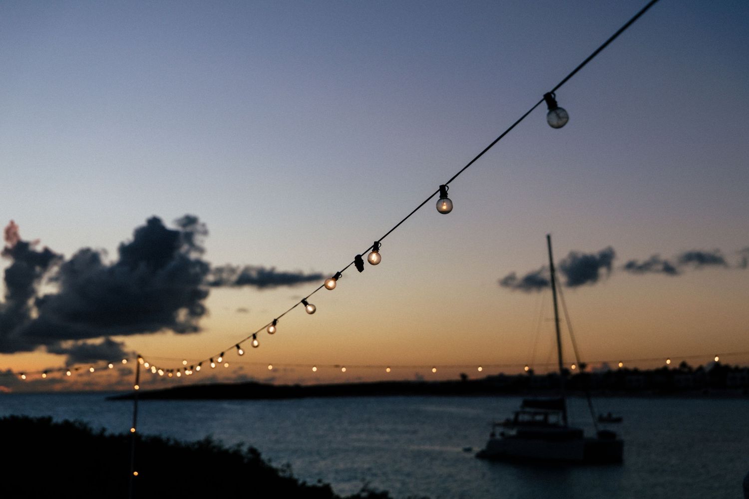 String lights hang across twilight sky creating romantic ambiance at outdoor venue.