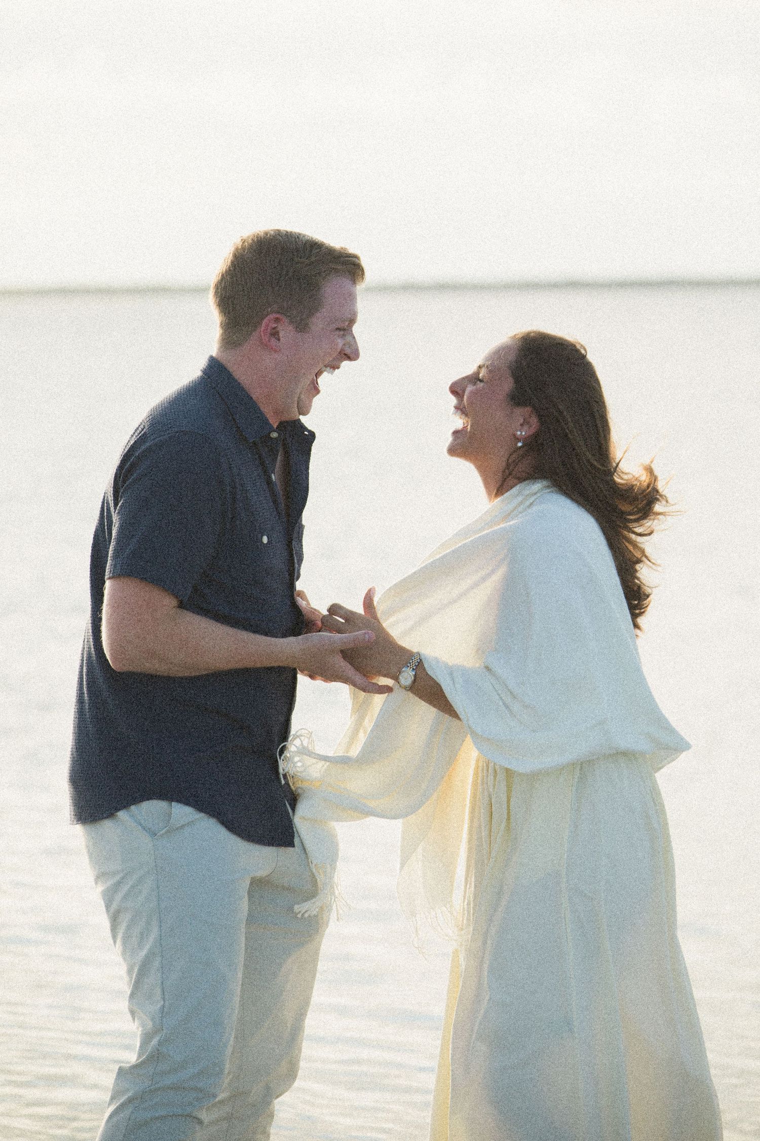 A couple shares an excited reaction during a special moment by the water.