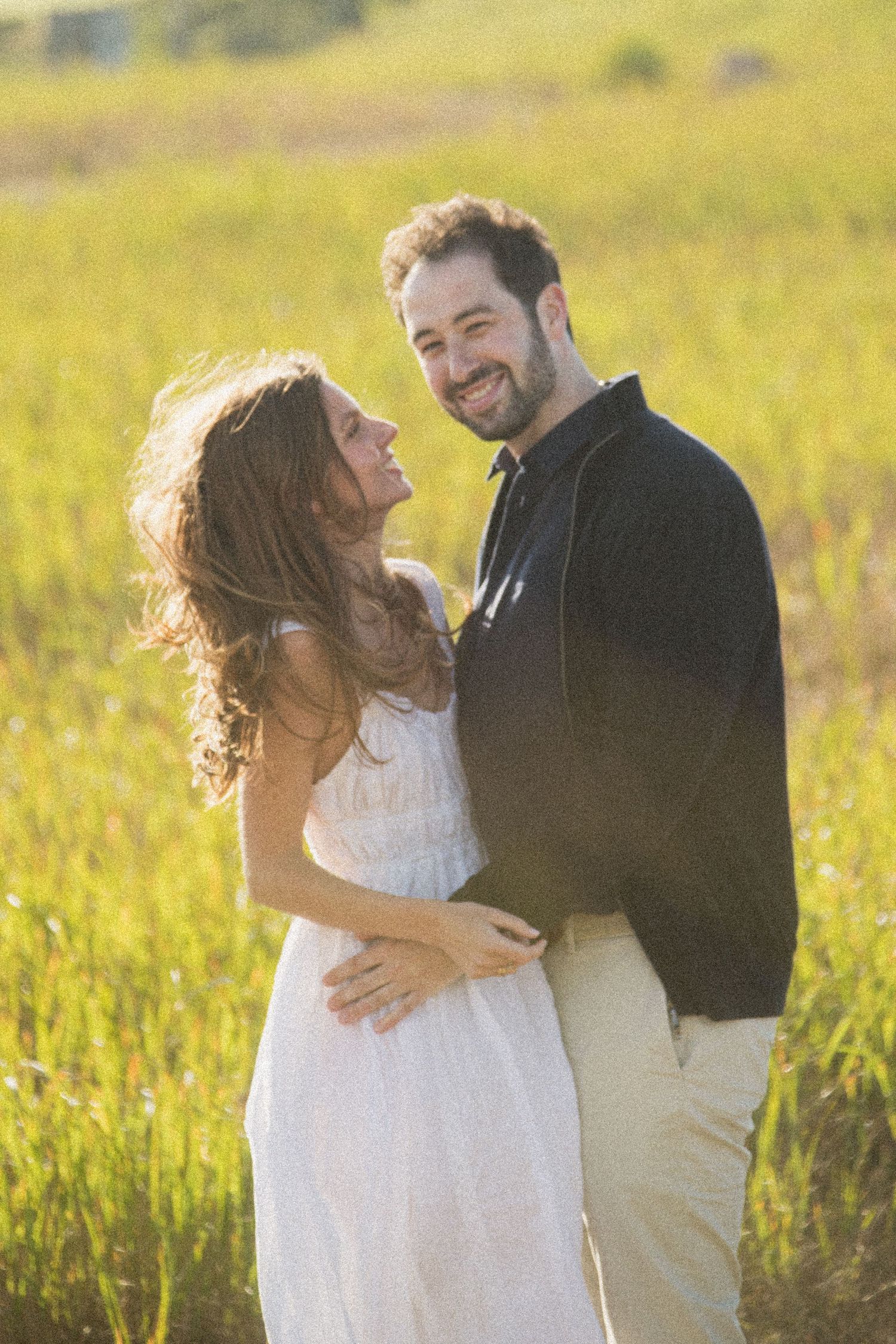 A couple shares intimate moments while dancing in a sun-drenched field.