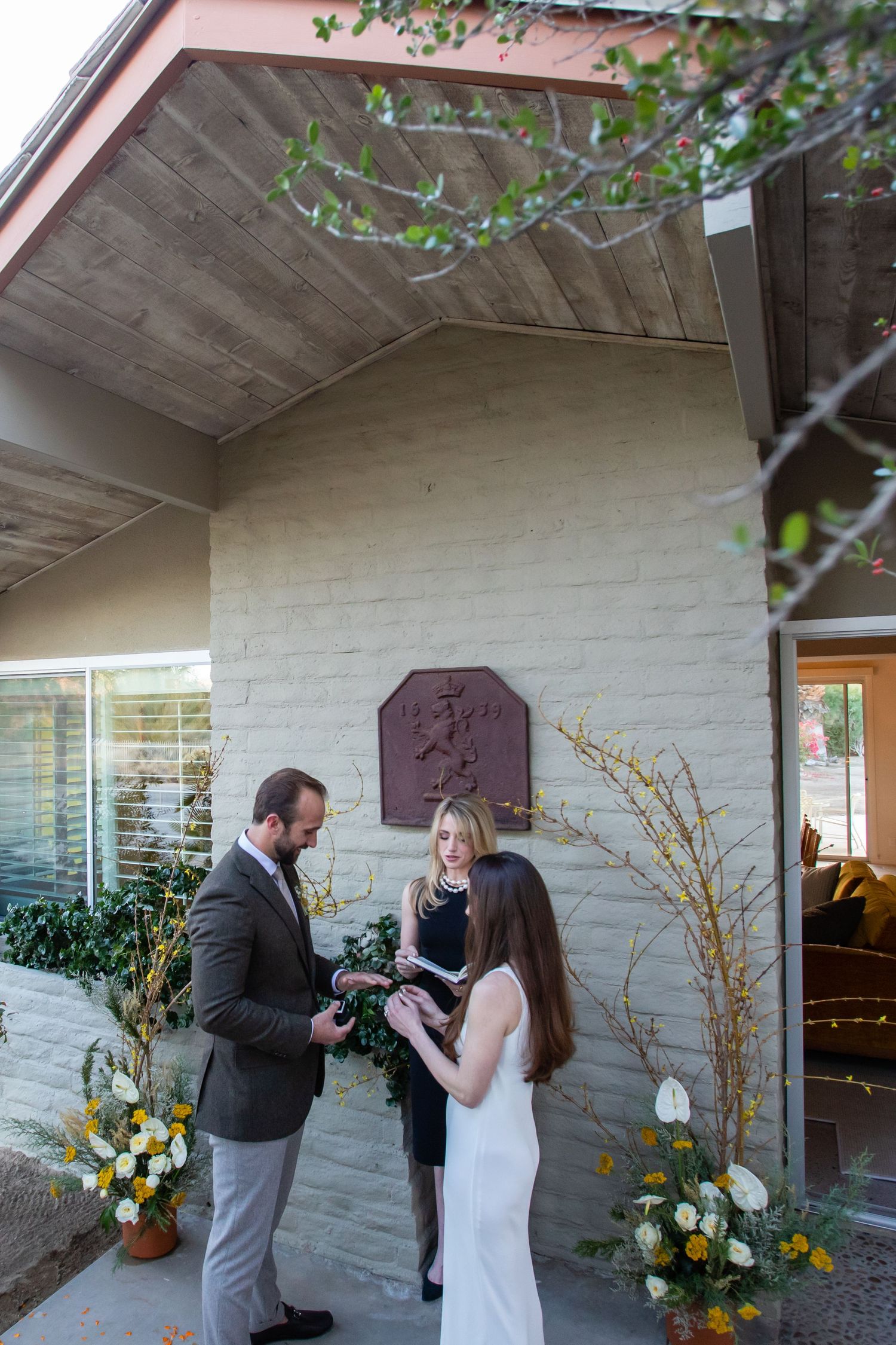 A series of photos capturing a surprise proposal moment against a white brick wall with floral decorations.