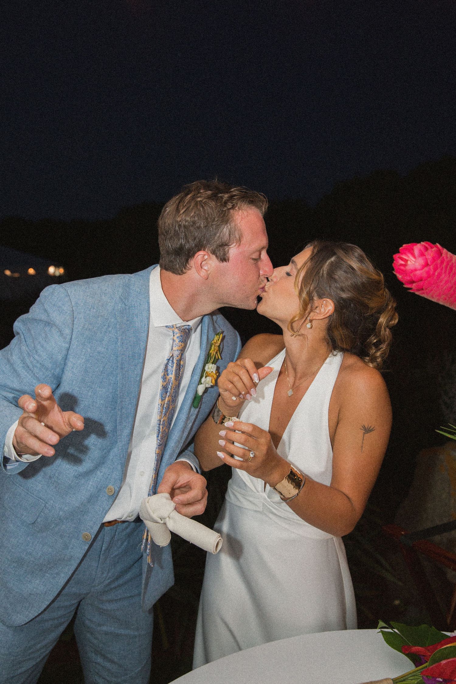 Newlyweds enjoying a messy and fun cake-feeding moment at their reception.