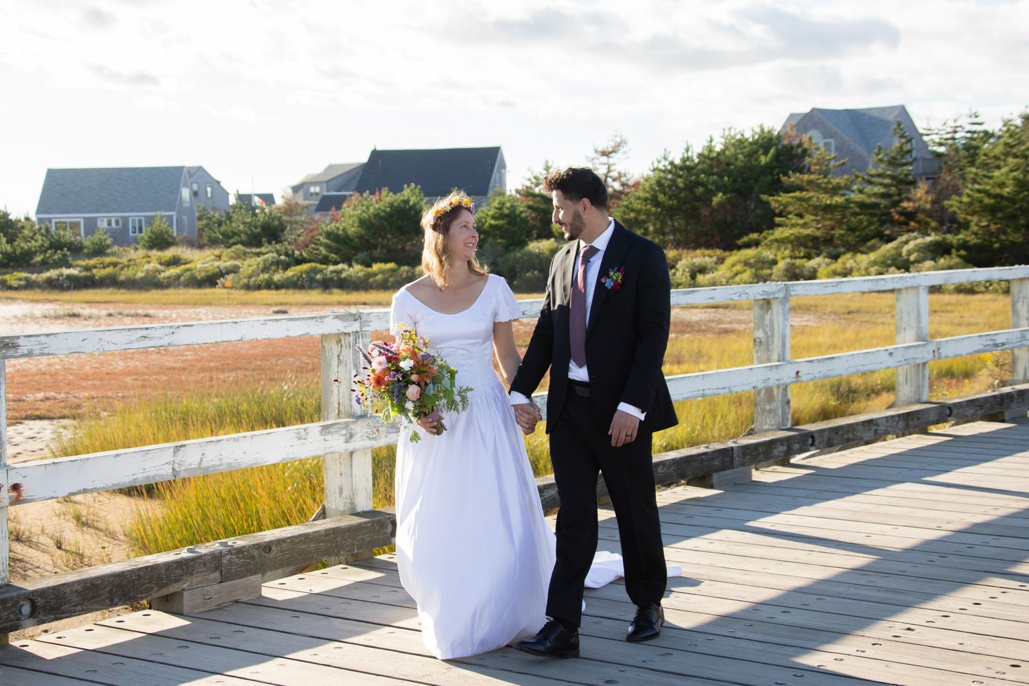 Elegant wedding couple taking photos on a boardwalk with marsh views.