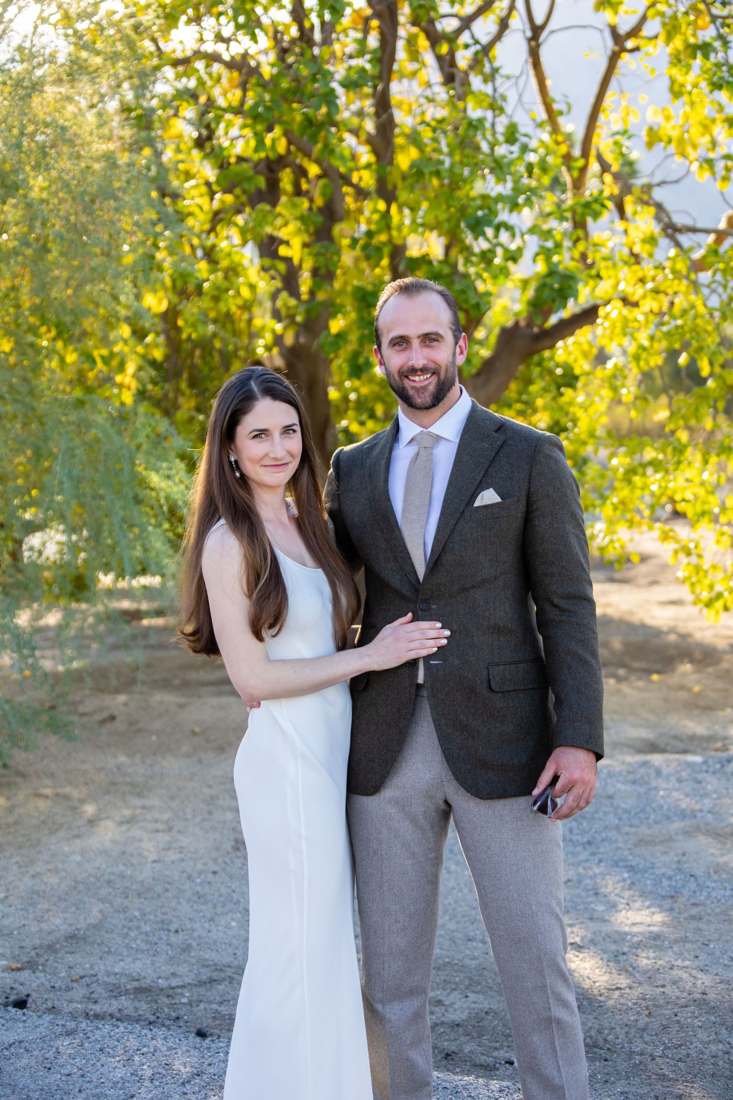 Couple in formal wear posing together on outdoor path.