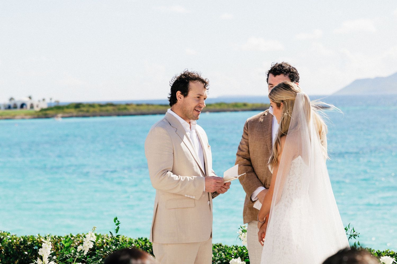 Wedding celebration on a tropical beach deck with crystal clear waters and mountains in the distance.