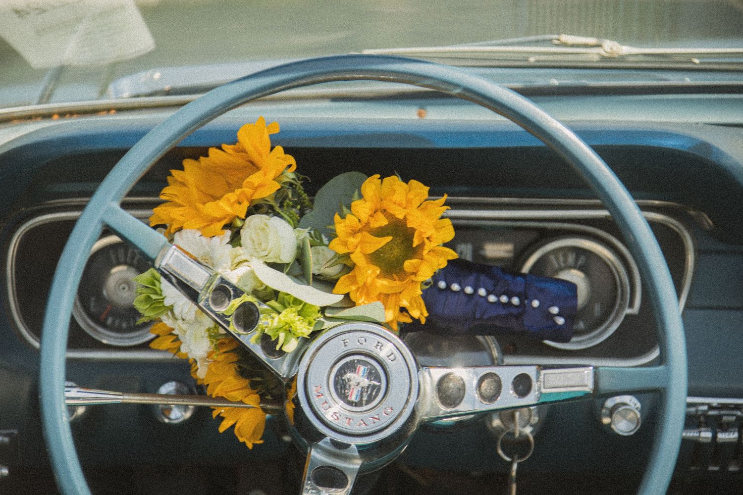 Dashboard of classic Ford Mustang decorated with yellow sunflowers.