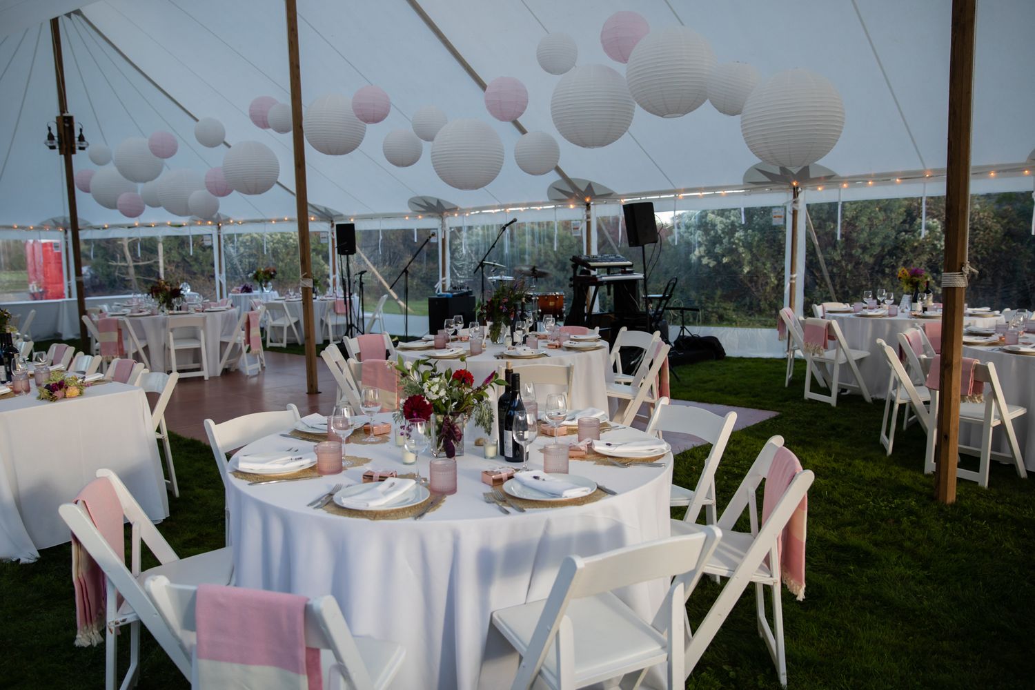 White tent wedding reception setup with round tables and balloon decorations.
