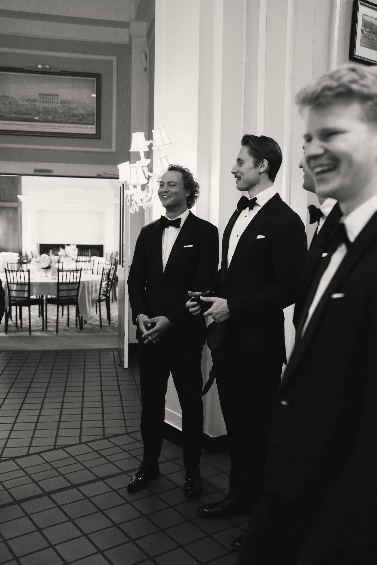Groomsmen in formal black tuxedos gathered in conversation before the ceremony.