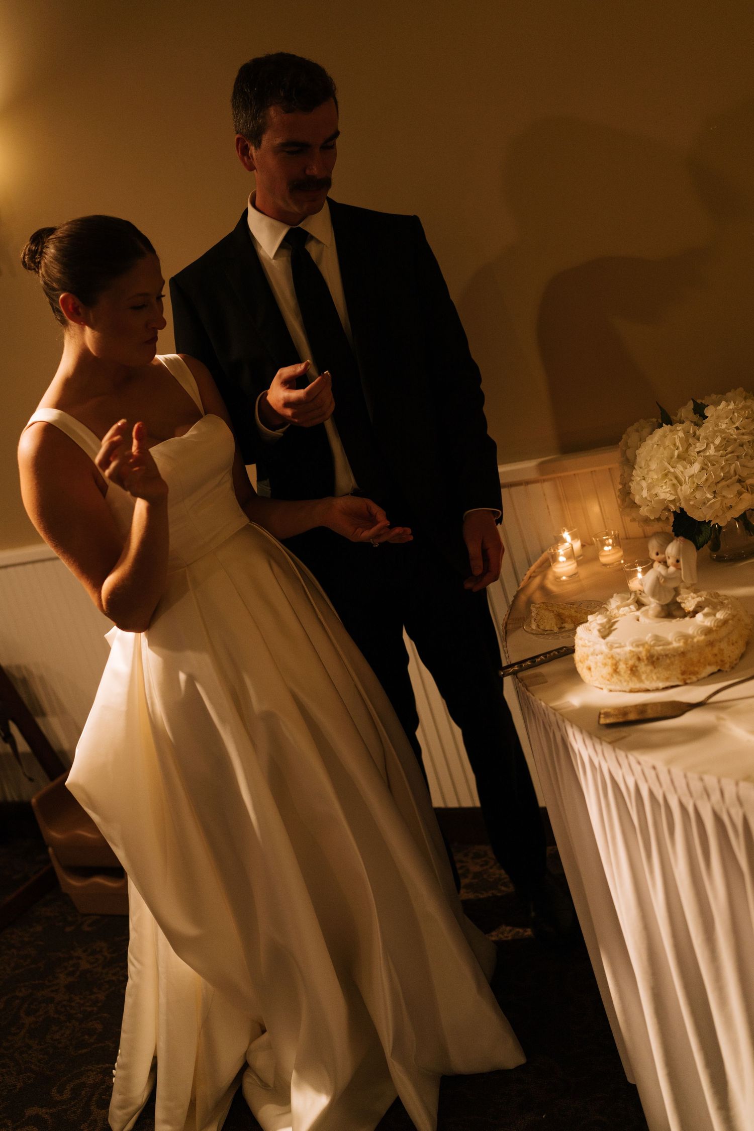 Couple cutting their wedding cake in romantic candlelight.