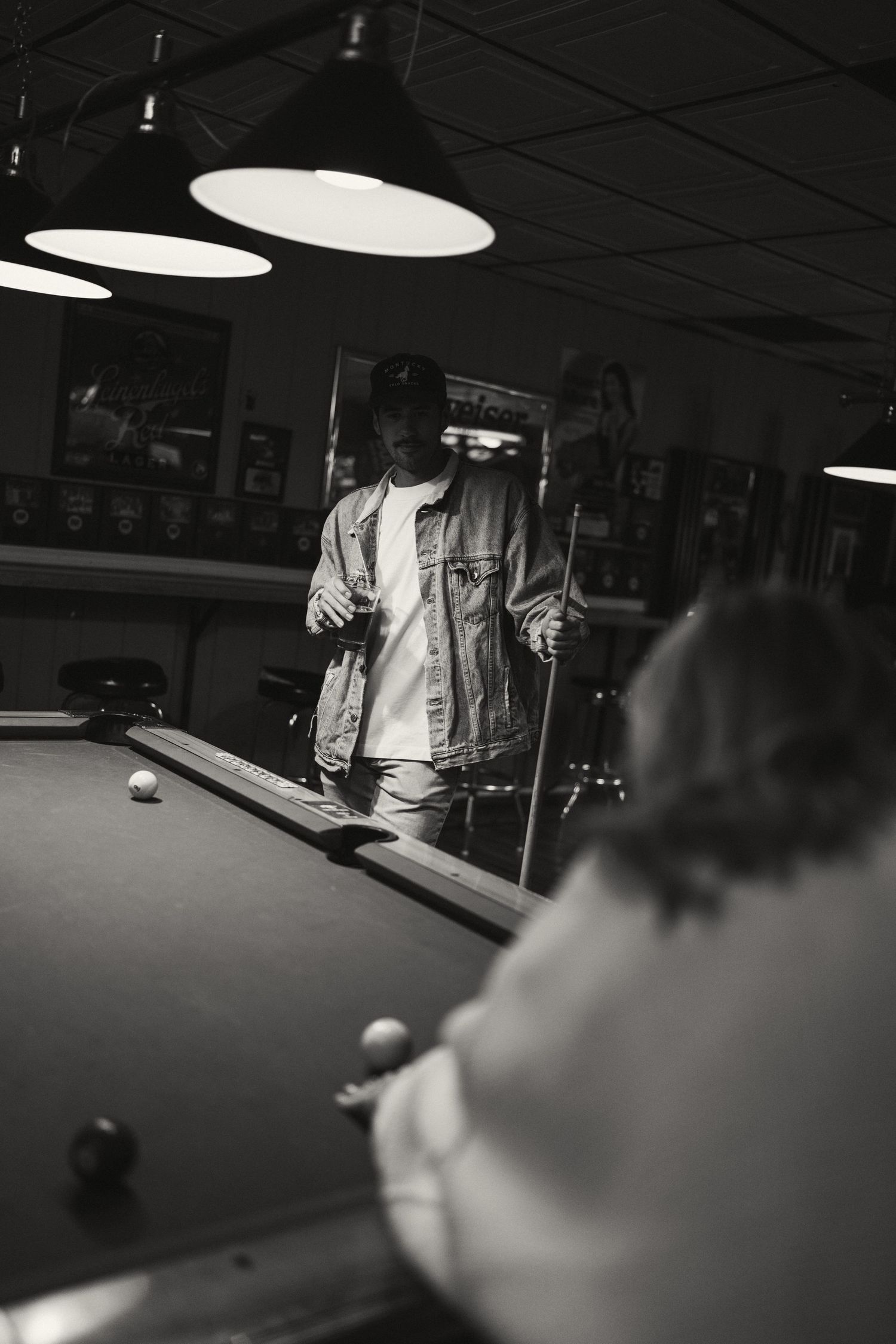 Black and white photo of billiards game in progress on pool table.