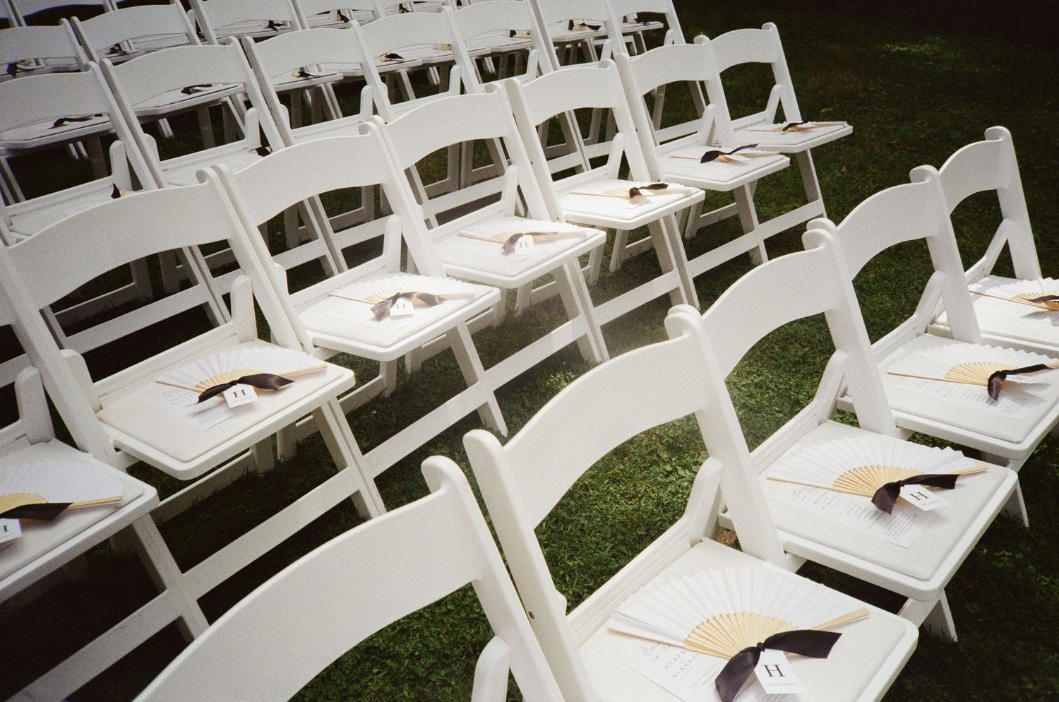 Rows of white folding chairs set up for an outdoor wedding ceremony.