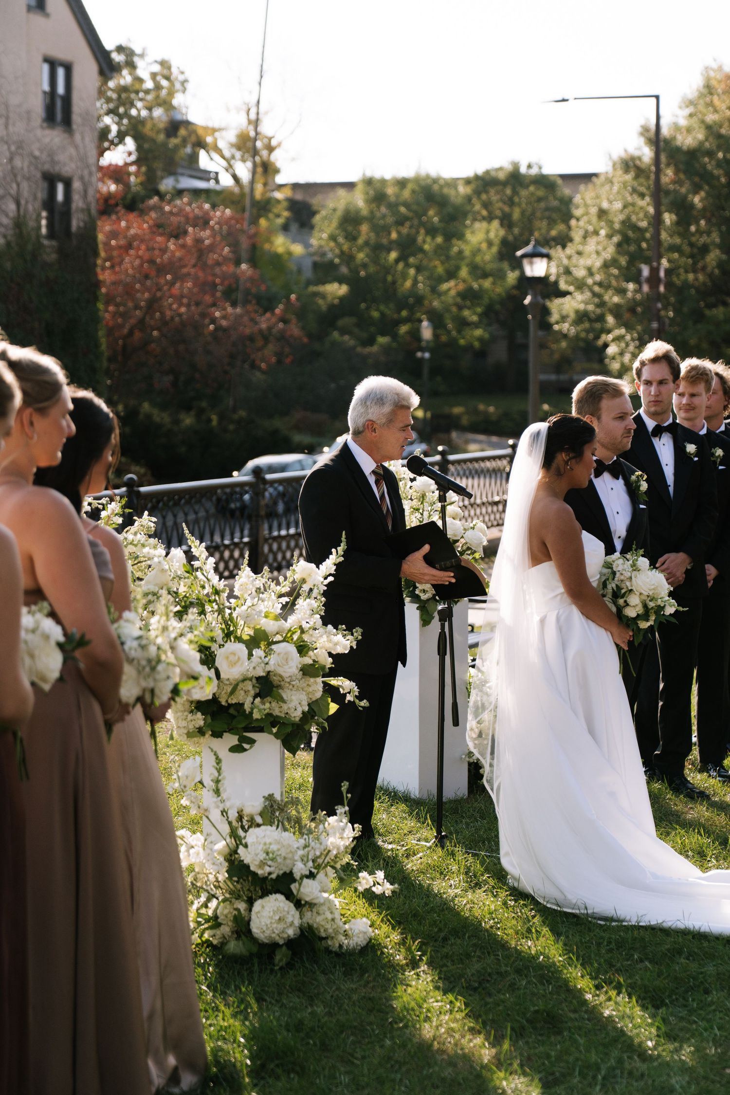 Outdoor wedding ceremony setup with white floral arrangements and brown bridesmaid dresses.