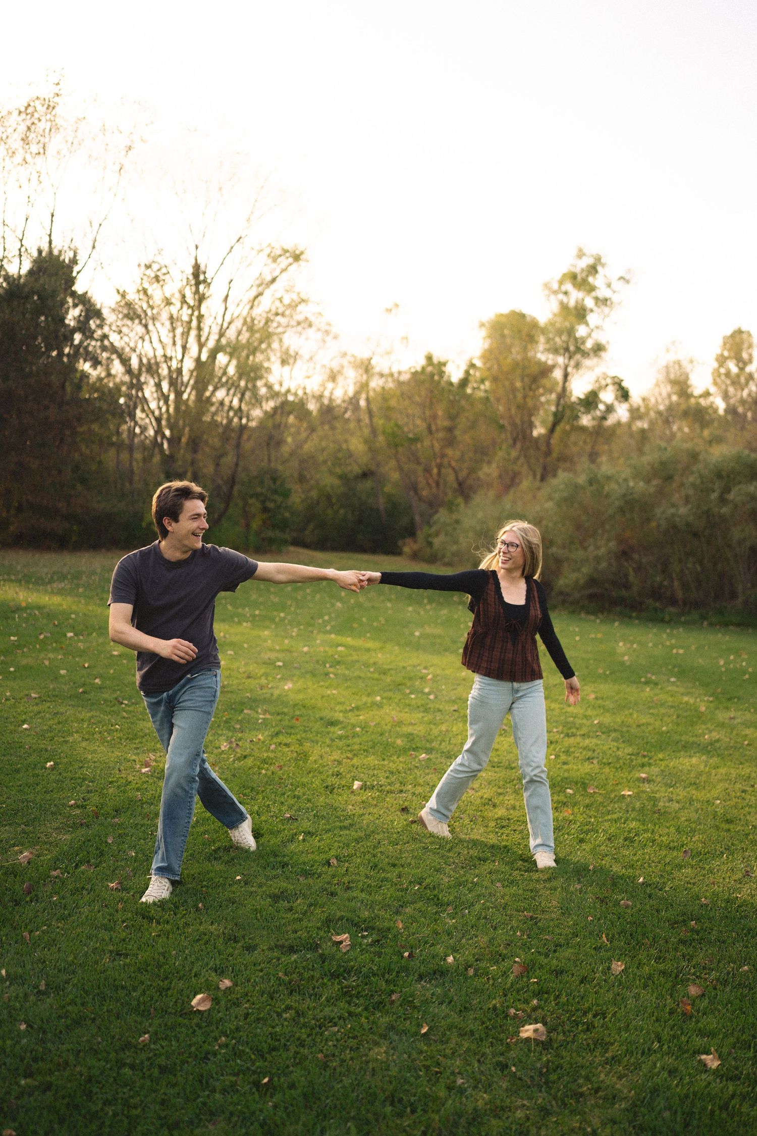 A playful sequence of two people dancing and spinning on green grass at sunset.