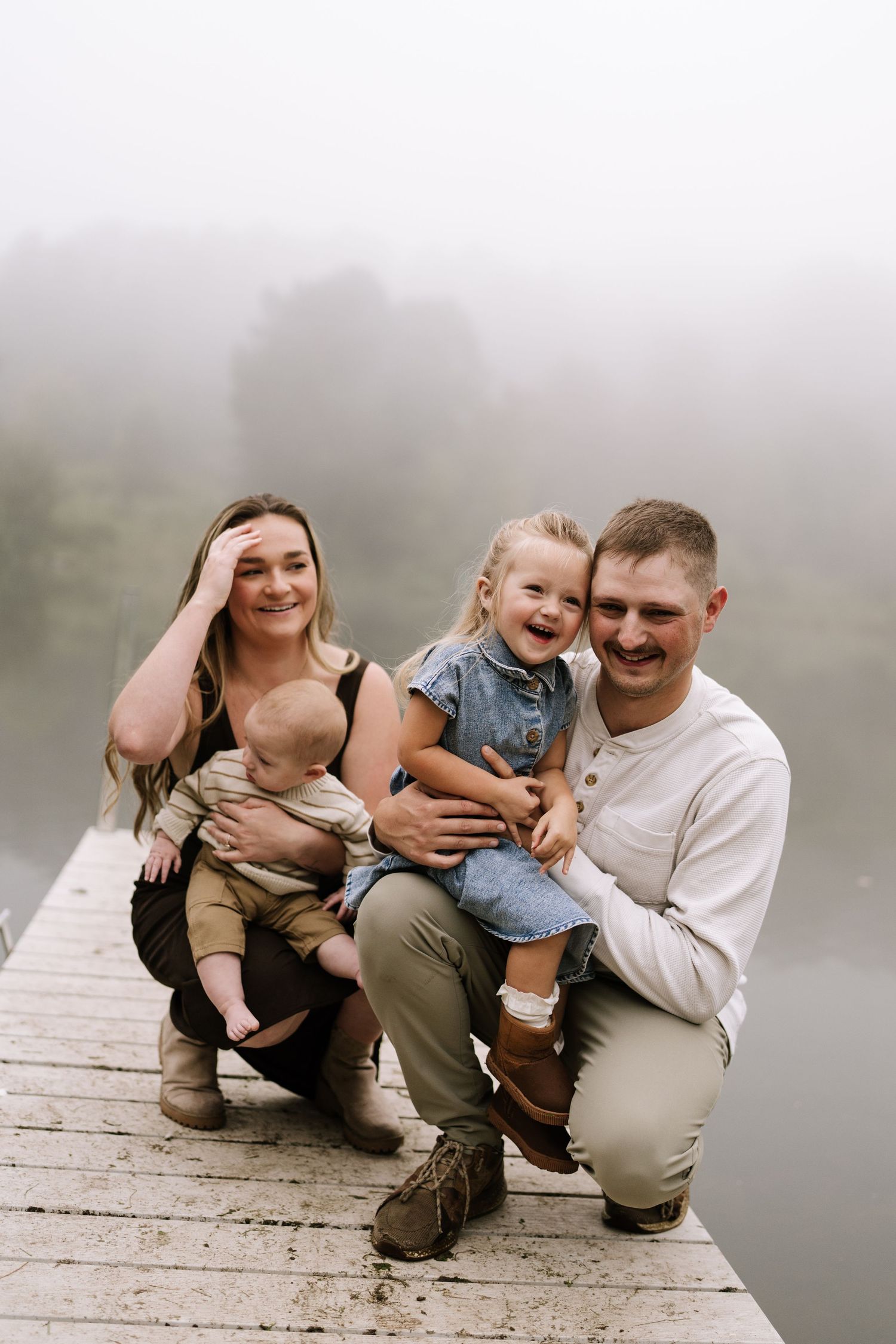 A casual outdoor photo session on a wooden dock by a foggy lake.