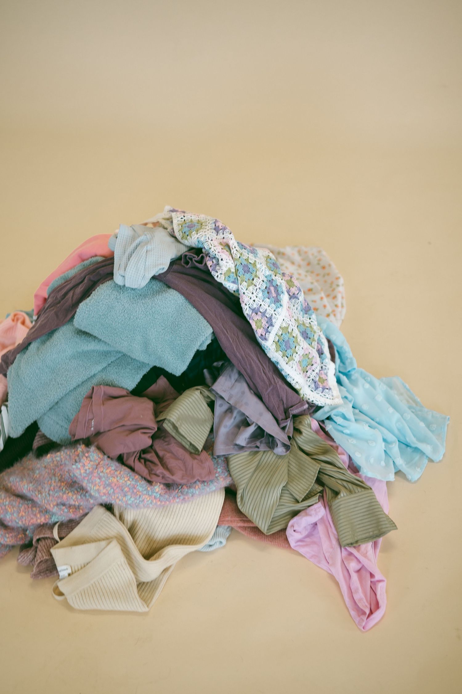 A collection of folded pastel and neutral colored clothing items arranged in a row.