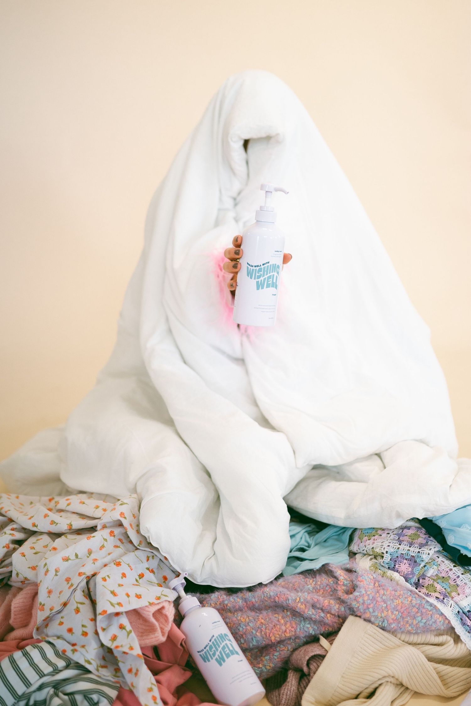 A white comforter or blanket draped over colorful patterned fabrics and clothing.