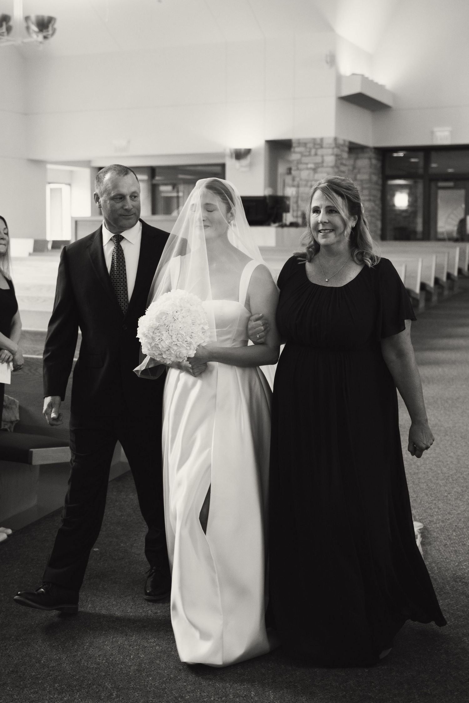 Wedding party walking through indoor venue in formal attire.