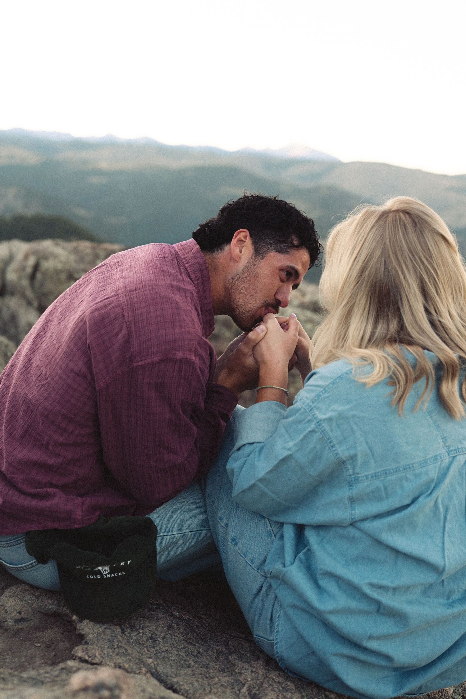 Couple shares intimate moment while lying on mountain rocks.