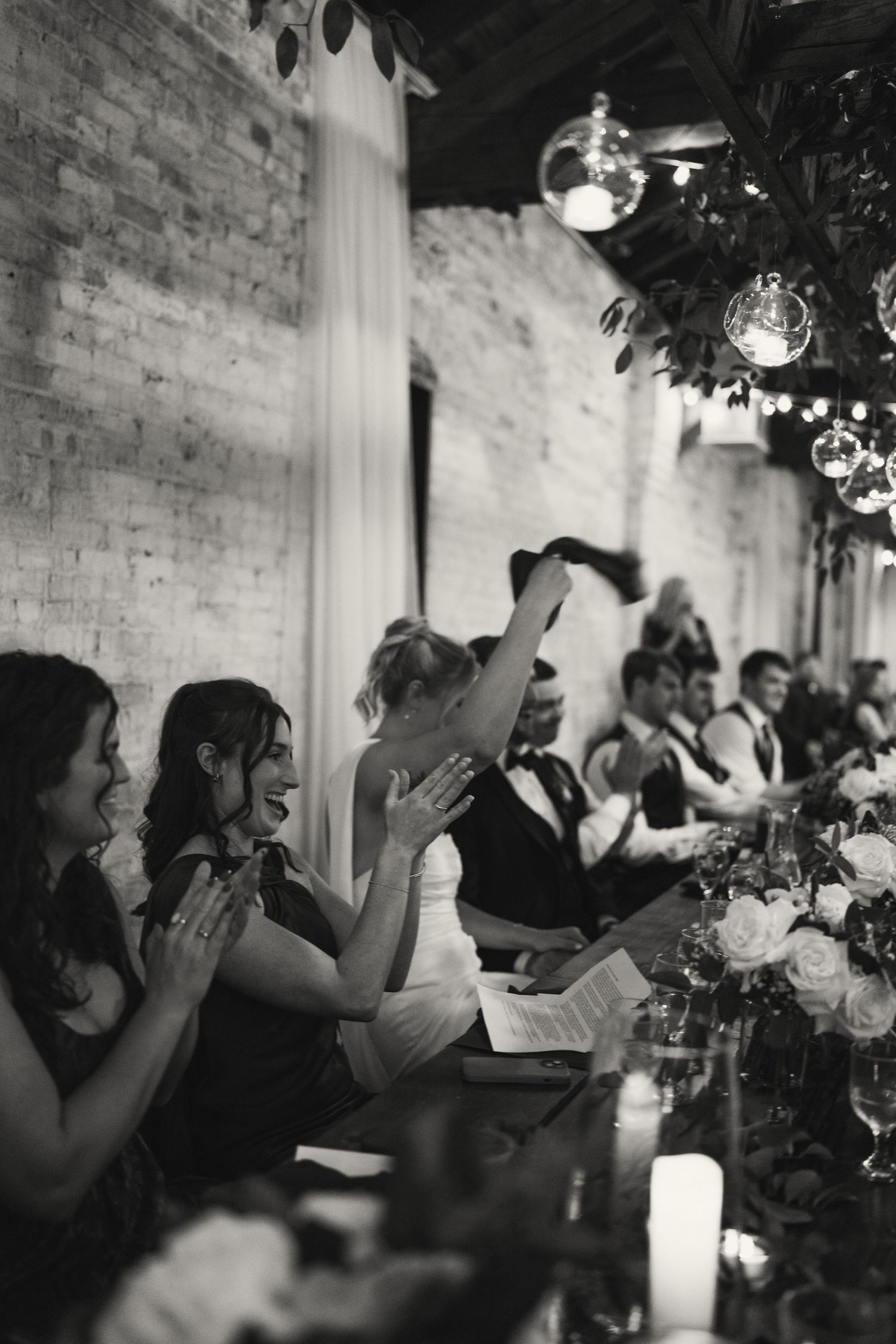 Wedding reception guests clapping and cheering during a celebration in an elegant venue.